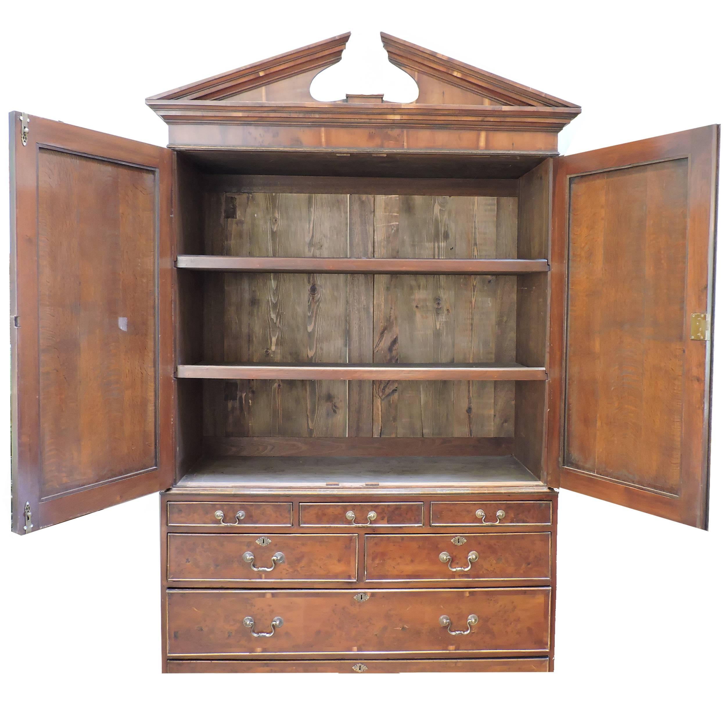 This George III solid mahogany linen press is monumental in stature. A two-door cabinet conceals rare original pullout drawers with a classical broken pediment above. A chest of drawers with original brass hardware anchors the piece. All drawers and