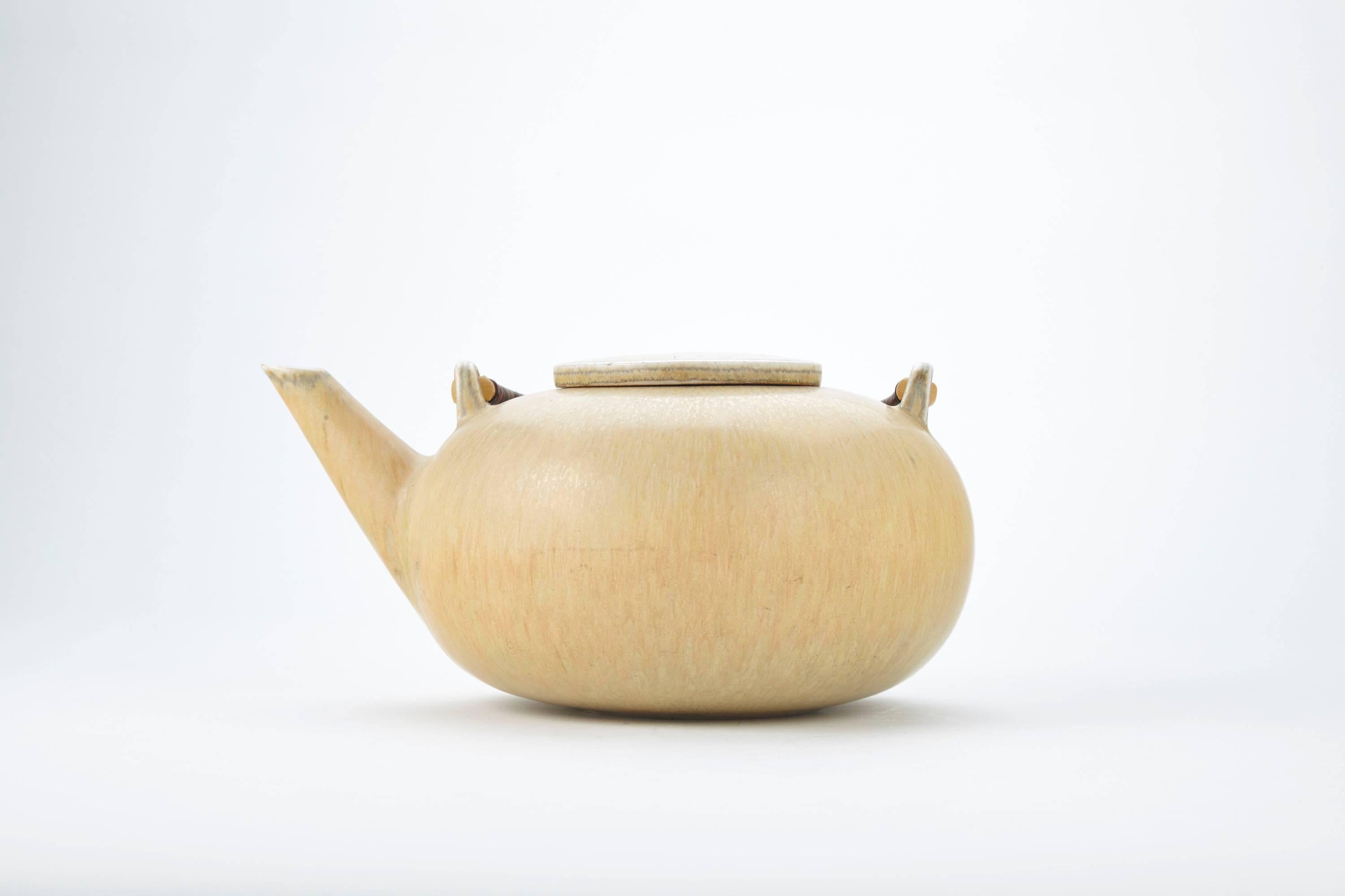 Glazed Saxbo teapot, probably designed by Eva Staehr Nielsen, from around the 1940s or 1950s. 

The stoneware teapot has a woven bamboo handle and is stamped Saxbo, Denmark and with the number 50. 

Saxbo (1930-1968) is now widely recognized as