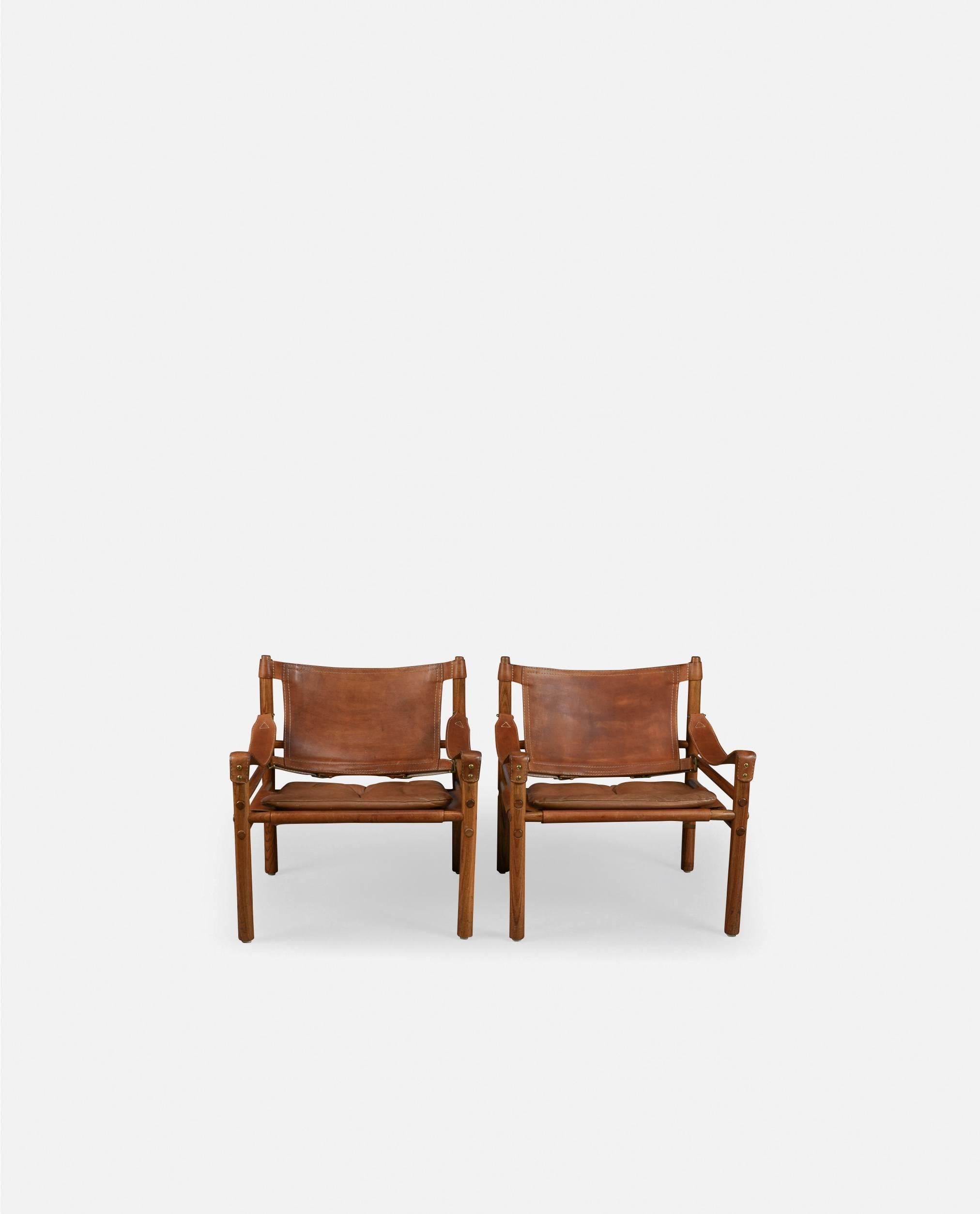 A beautiful original pair of Arne Norell safari sirocco chairs in rosewood and patinated brown leather, 1960s, Sweden. Made by Aneby Mobler, Sweden. Fast and inexpensive shipping worldwide. Will be disassembled for shipping but easy to assemble on