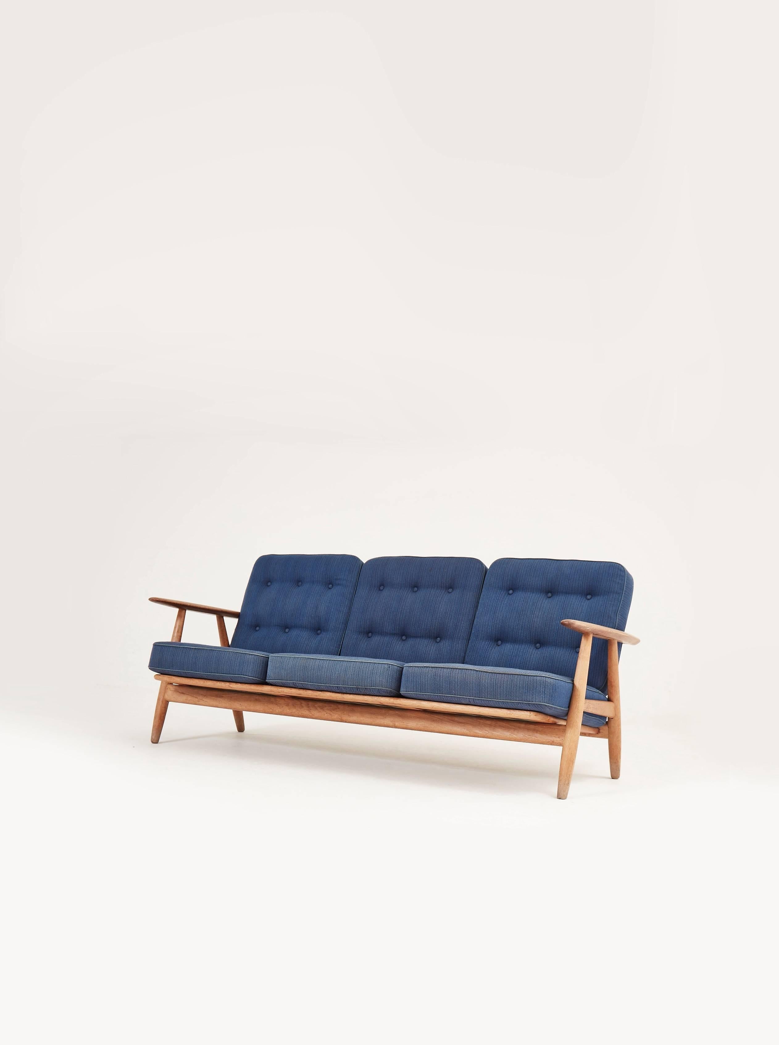 Early Hans Wegner oak cigar sofa, manufactured by GETAMA in Denmark, 1950s-1960s.

In original condition. Some signs of use and wear. Structurally sound, with beautiful all oak frame with some light marks, and original sprung cushions. Original