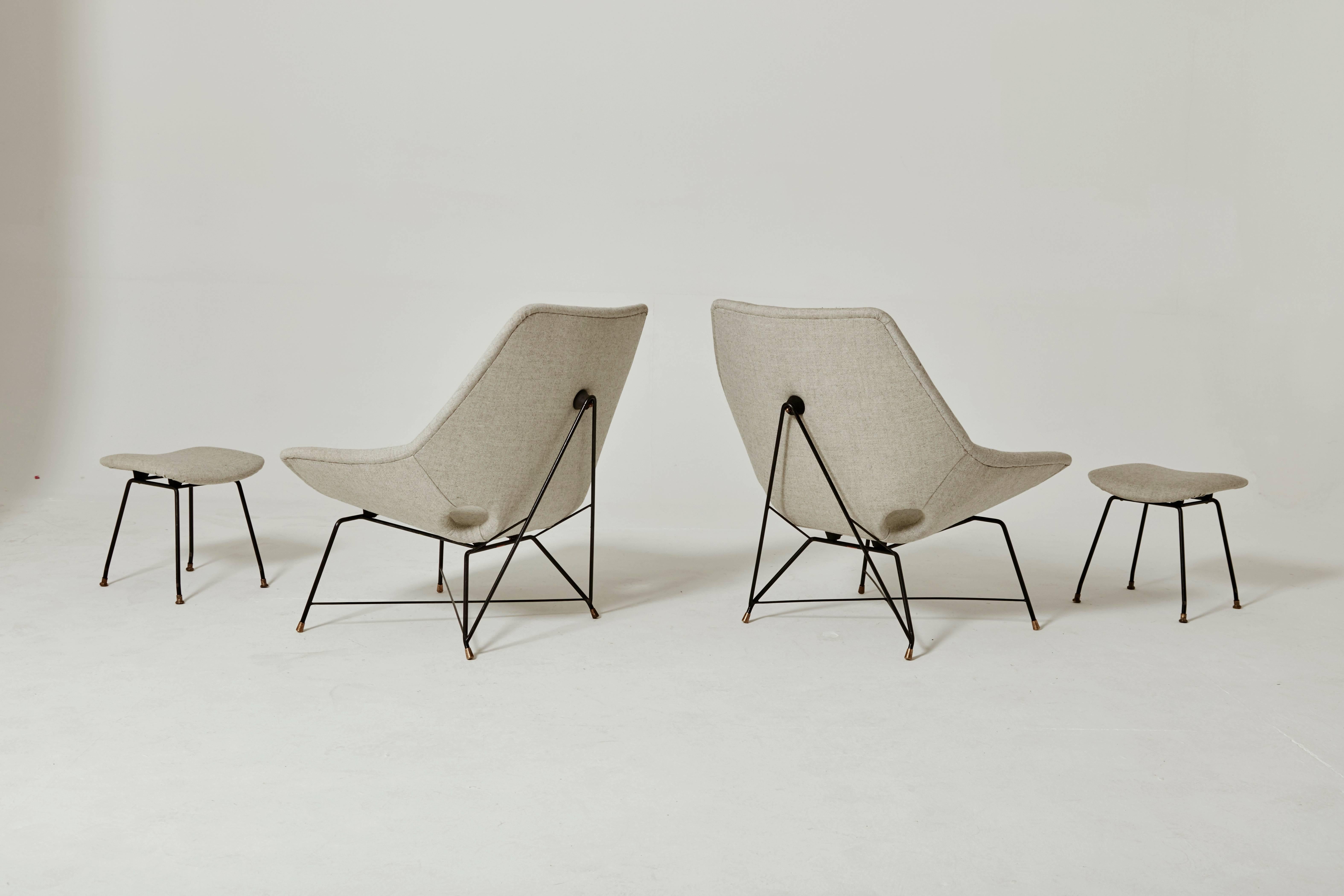 A wonderful and rare pair of lounge chairs with ottomans designed by Augusto Bozzi for Saporiti Italia, Italy 1954. The chairs and stools have a black lacquered metal base with solid brass feet and are newly upholstered in Kvadrat wool fabric.