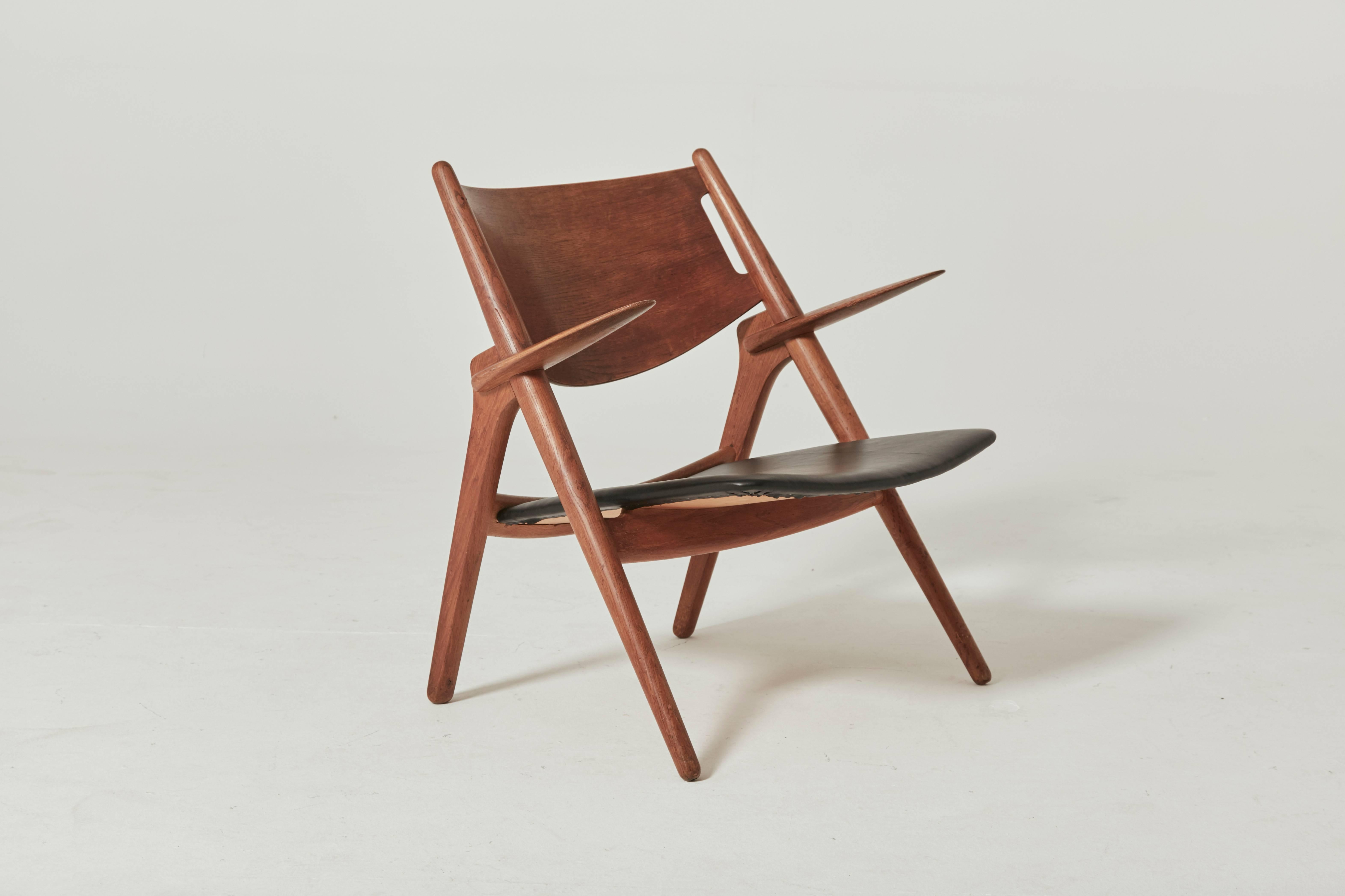 Early Hans Wegner CH-28 sawbuck armchair with leather seat. Ships worldwide.