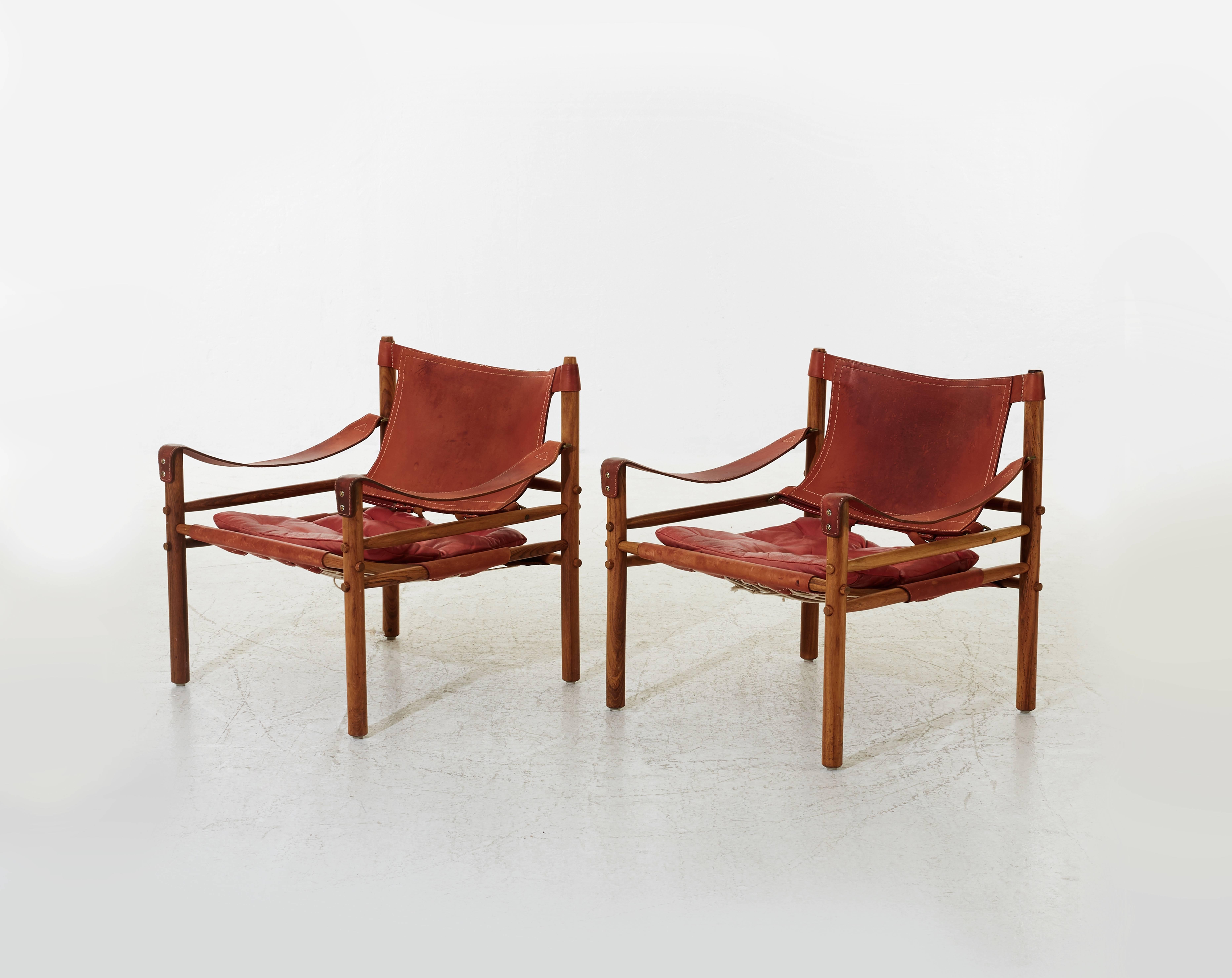 A stunning pair of authentic vintage Arne Norell safari sirocco chair in rosewood and rare red leather. Made by Norell Mobler in Sweden.

Ships worldwide.  The chairs will need to be disassembled for shipping but were designed to be taken apart and