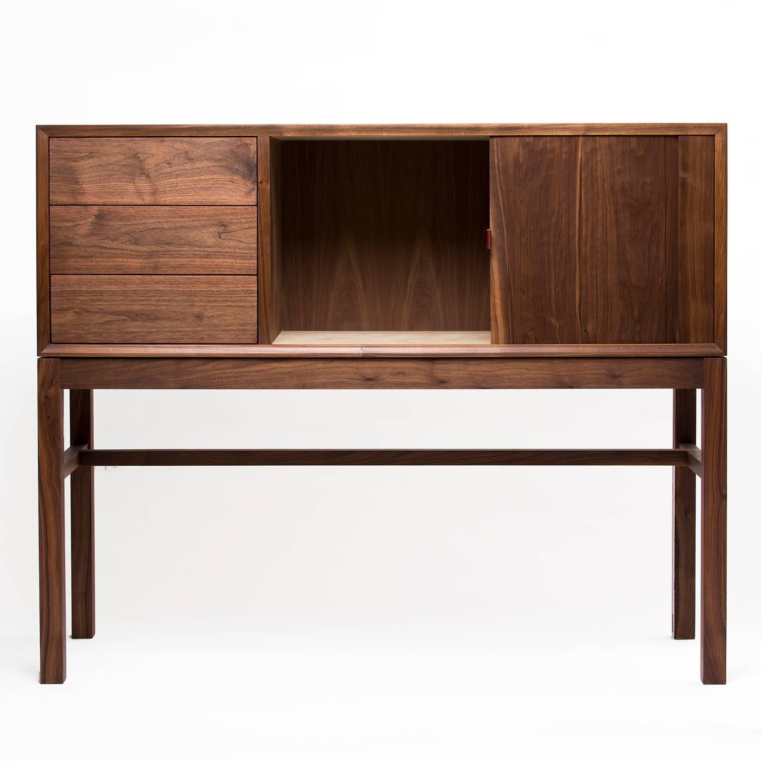 Walnut cabinet that can function as a sideboard, hutch or bar, with a tambour door that disappears to the right as you open. Hand-stitched leather pulls on the drawers and door, with solid maple drawer boxes and wood-on-wood drawer slides.