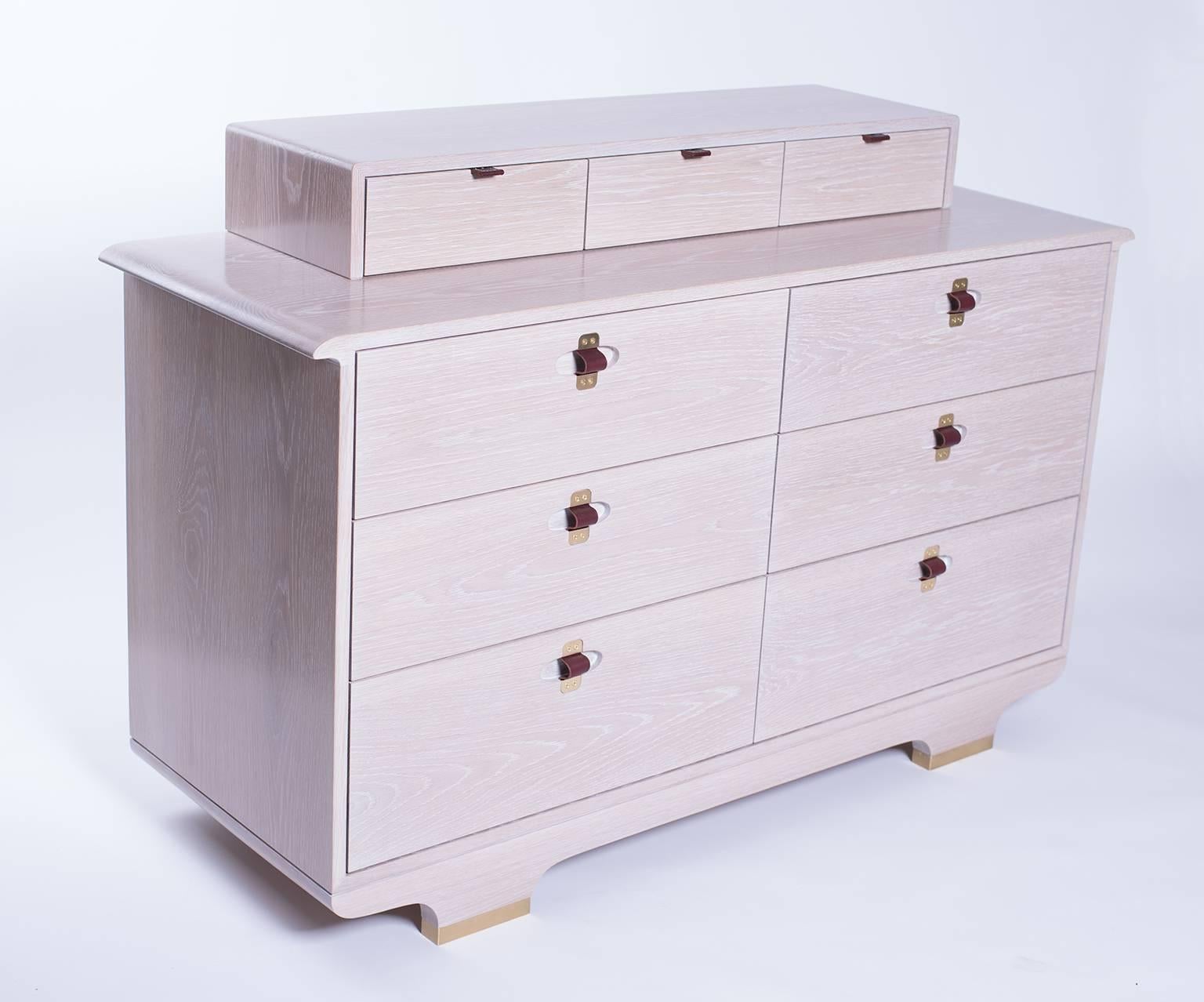 A nine drawer chest in white oak, with a whitewashed finish, brass/leather pulls, and brass feet. Also available without top row of small drawers.