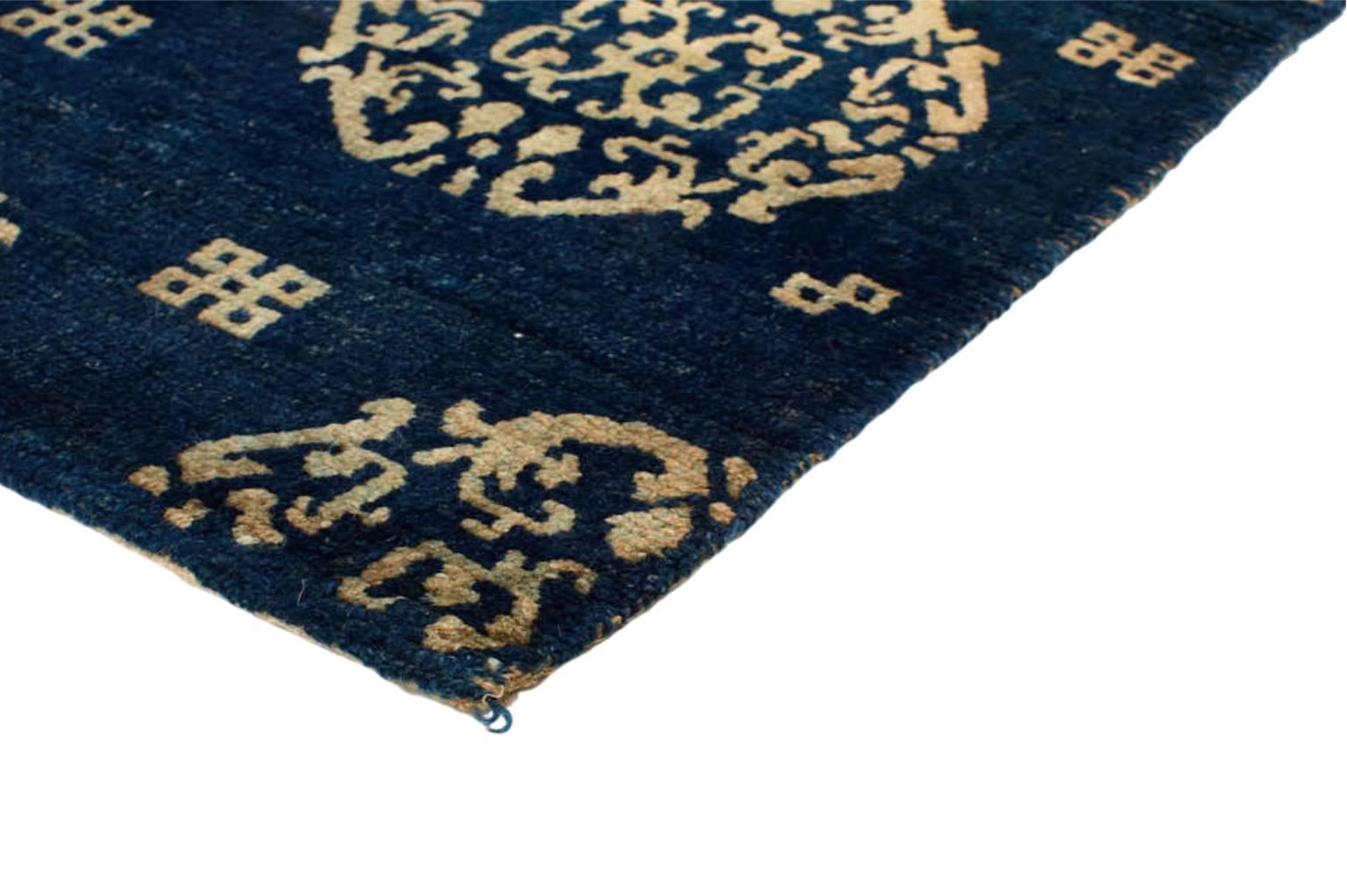 Individually selected by Madeline during her travels, this traditional palette of navy and ivory tonalities highlights the spiritual motifs and design of this antique Tibetan wool rug. The mandala motif represents various cultural beliefs inspired
