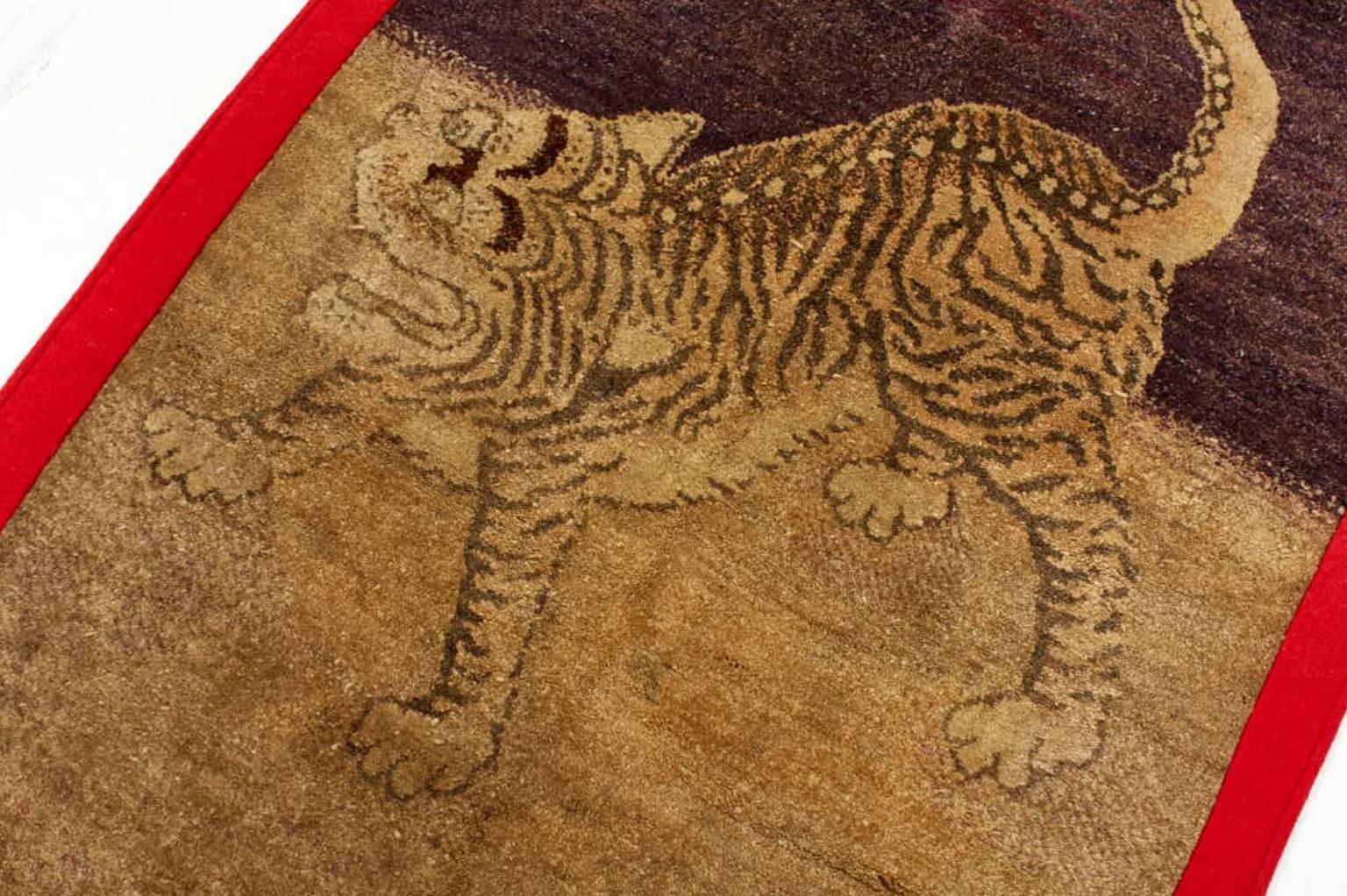 Individually selected by Madeline during her travels, this hand-knotted rug from Nepal features a Tibetan tiger in earthy hues and bold crimson border.