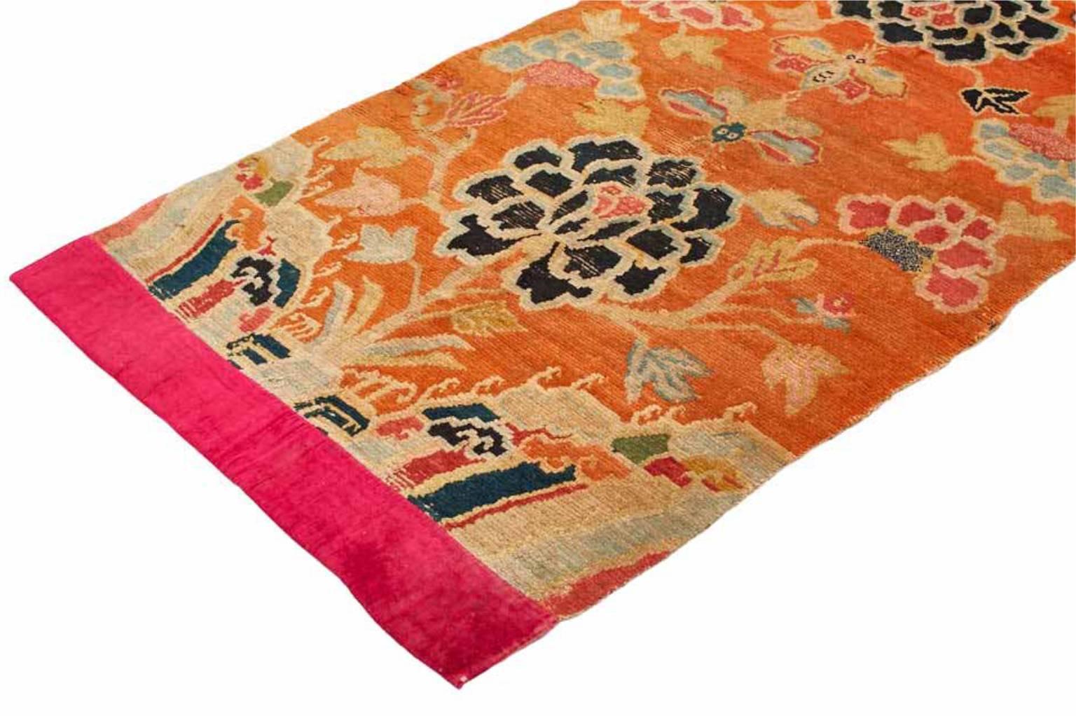 Individually selected by Madeline during her travels, this handwoven vintage Tibetan wool rug features lotus florals emerging from a saturated field. This distinctive palette of orange, pink, ivory, and navy hues emphasize the exotic beauty of this
