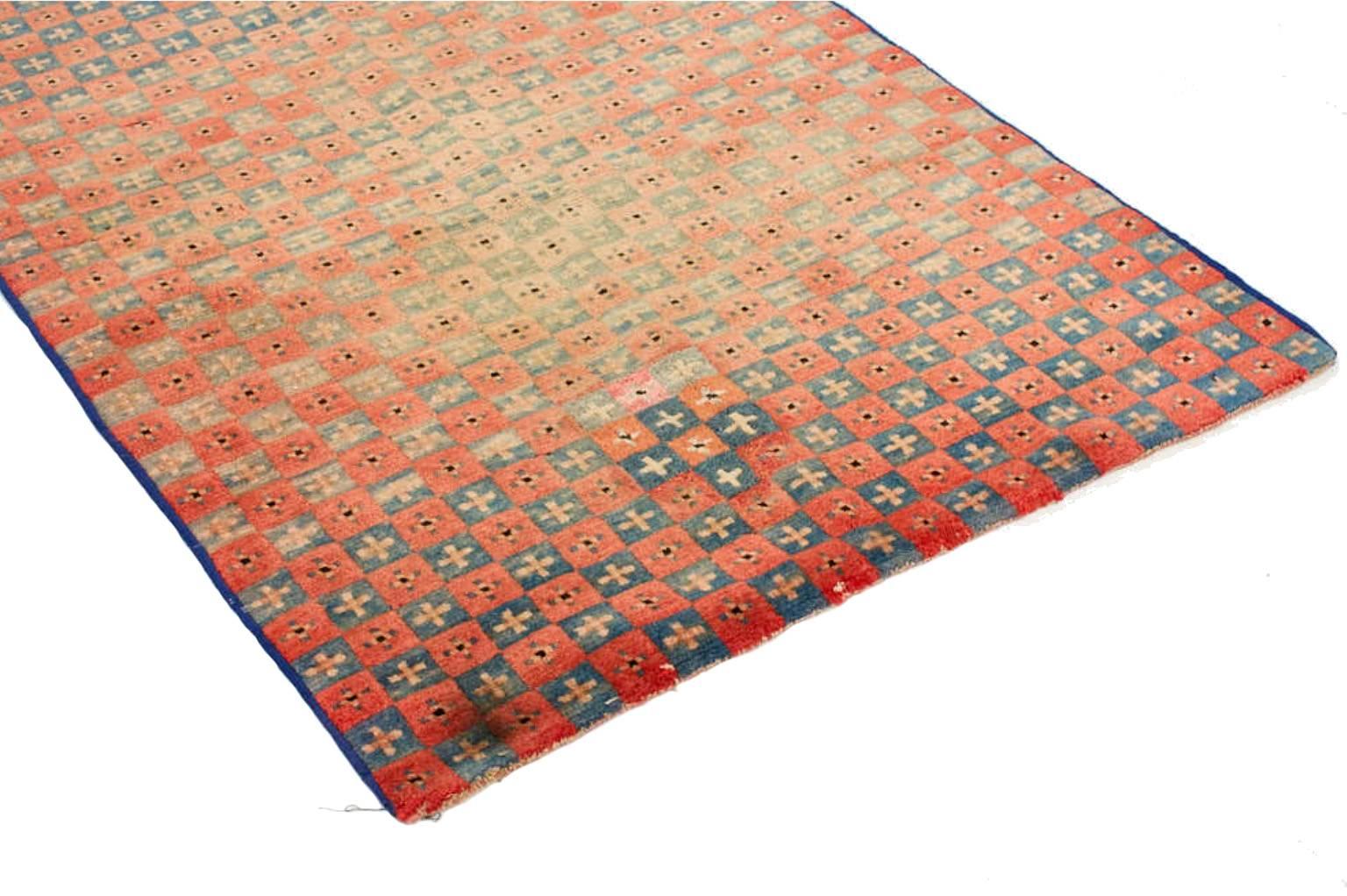 Individually selected by Madeline during her travels, this vintage Tibetan rug features an all-over checkerboard pattern rendered in blue, green and dusty rose hues. Handwoven from wool, nomadic artisans often created bold, geometric designs into