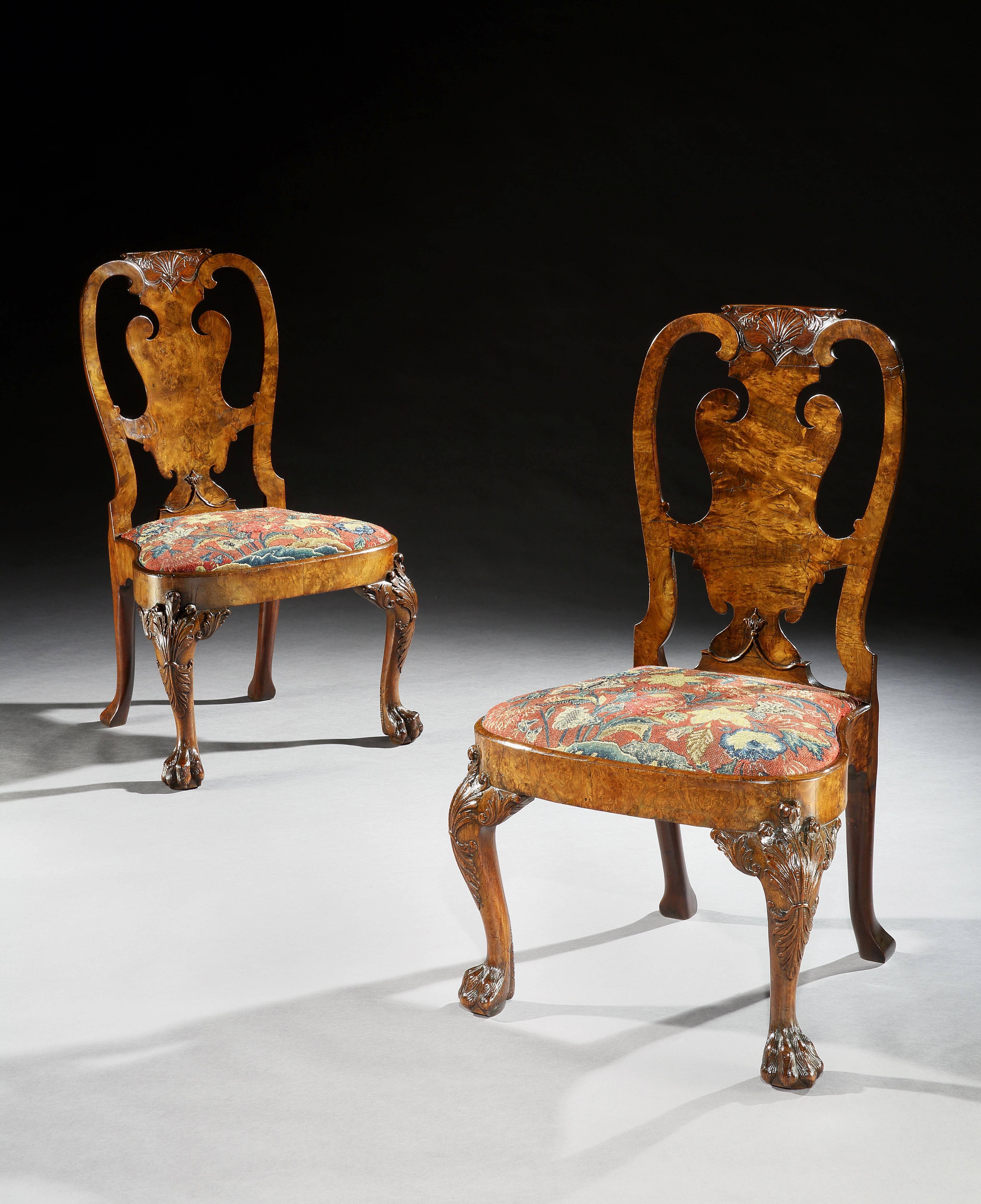 An important and very well documented pair of early George II side chairs in well figured veneered walnut and burr walnut, the carved shaped top rails centered by a shell above a shaped splat and with shaped seats covered in floral gros point and