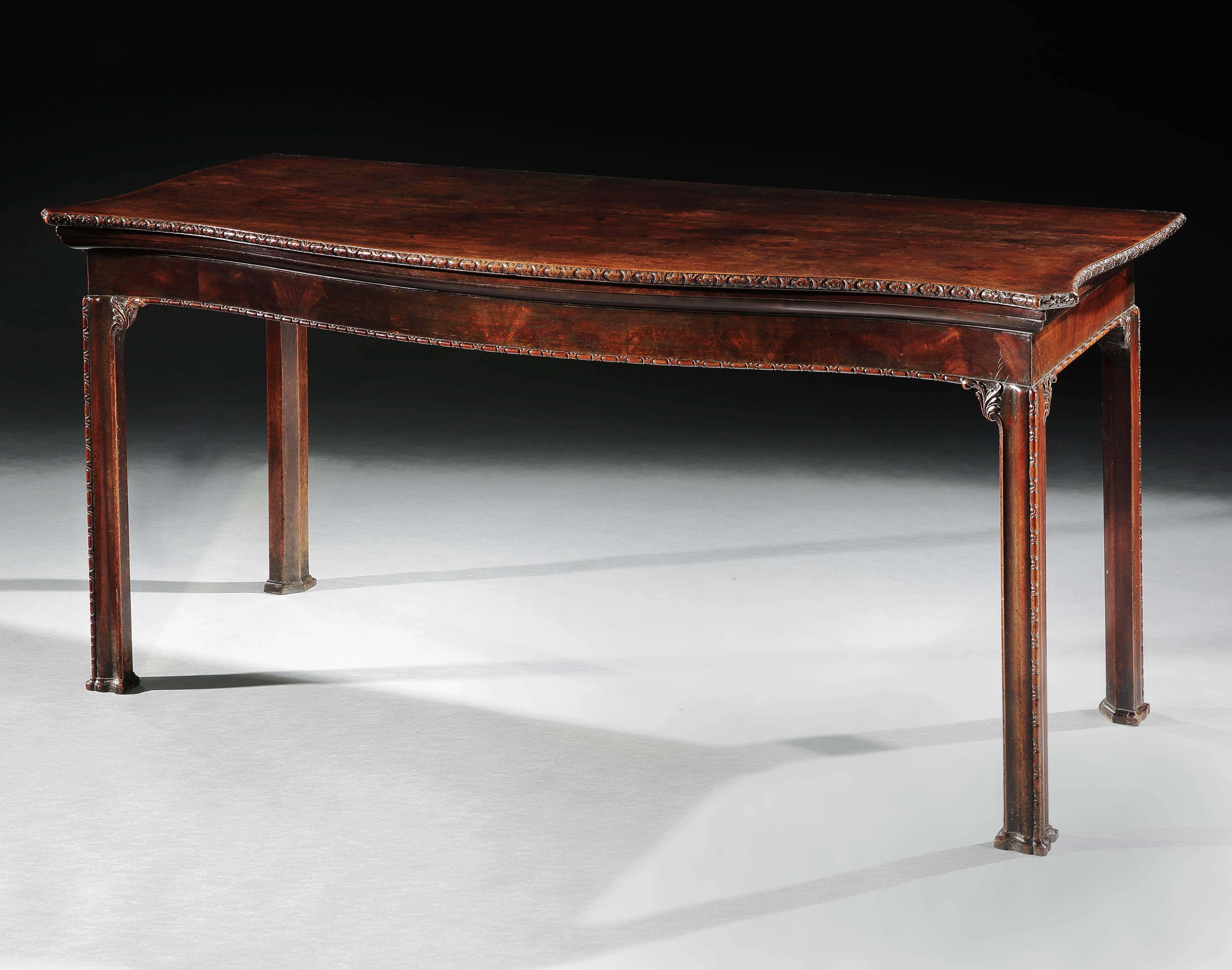 A fine George III mahogany serving table, the serpentine top, with a carved edge above a conforming frieze. The legs all similarly carved, and headed by brackets and terminating in block toes.