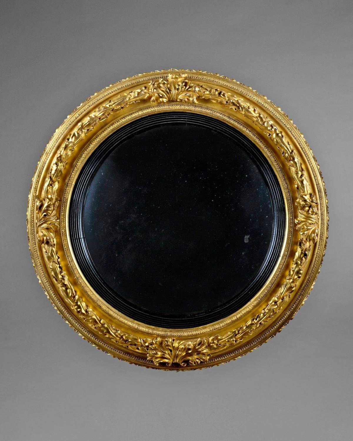 An elegant Regency period gilded convex mirror, profusely carved with acanthus and egg and dart decoration with a inset ebony moulding.
 