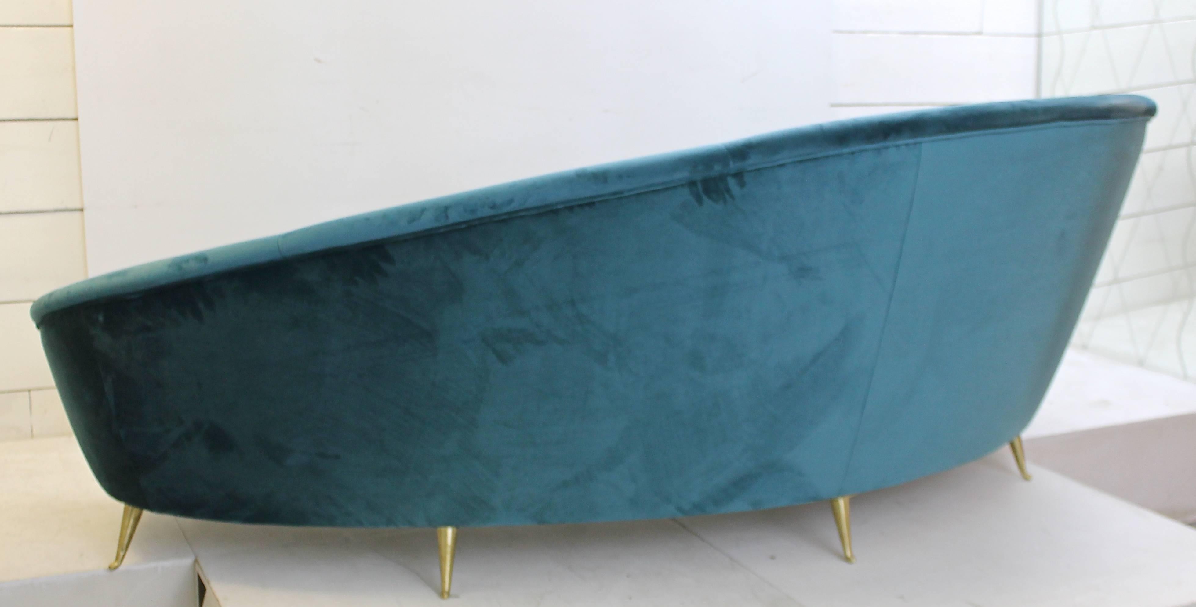 A 1950s Italian curved sofa, new upholstery and small typical brass feet.