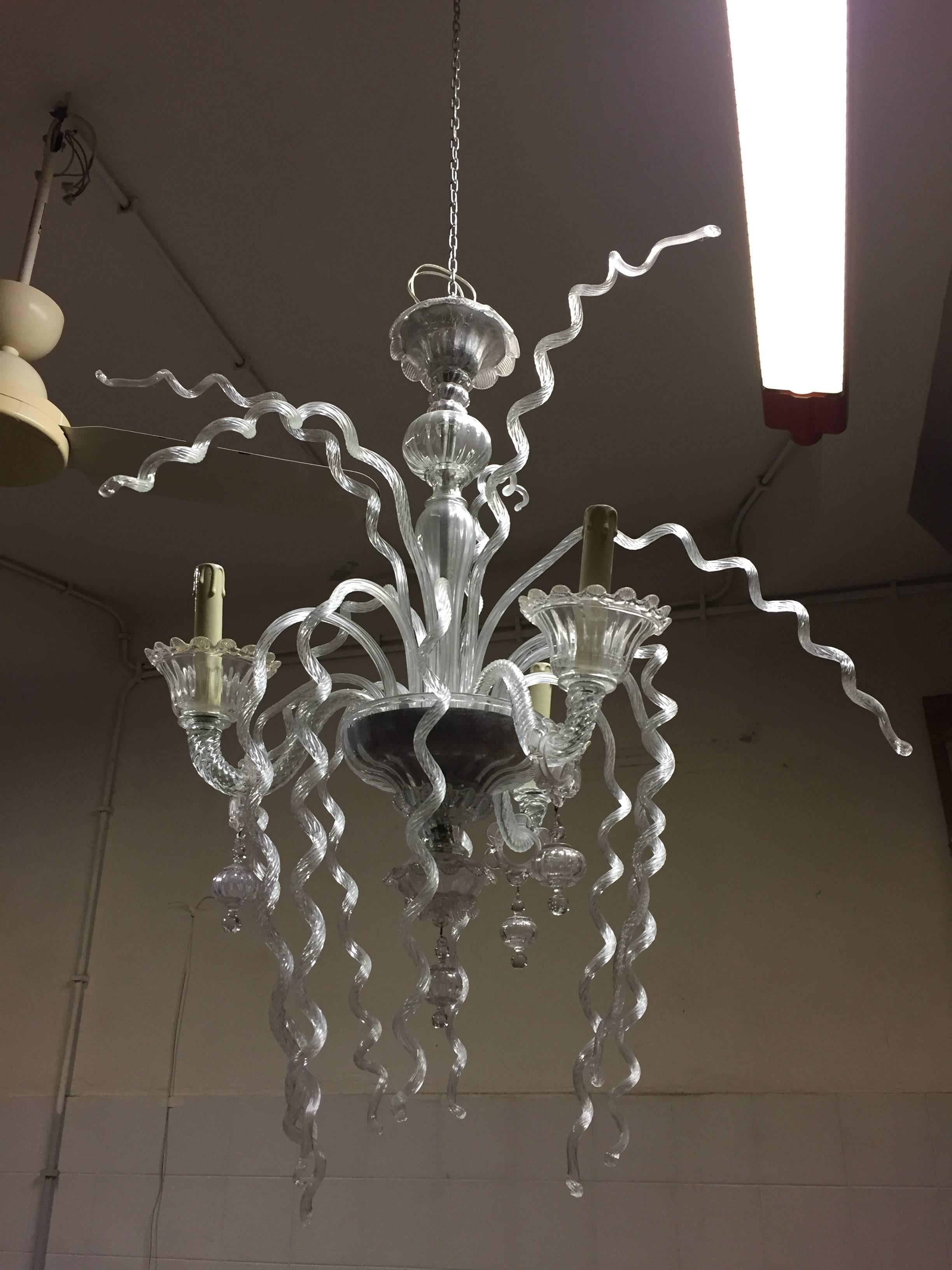 A beautiful three-arm Murano glass chandelier with curls decoration.