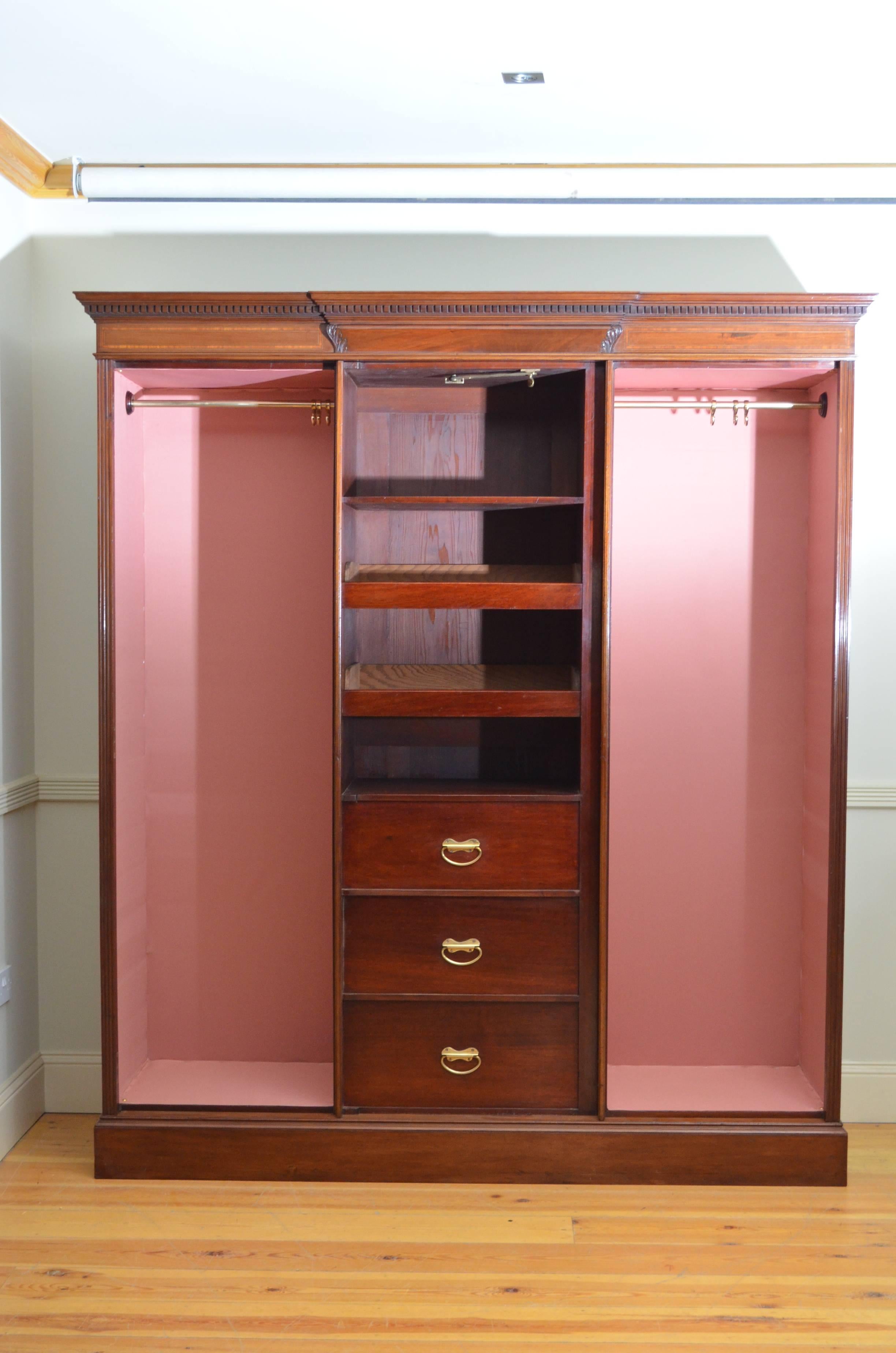 Sn3552, excellent quality and very impressive, Edwardian Shapland and Petter, three-door mahogany wardrobe, having moulded cornice with dentil caring and satinwood crossbanded frieze above centre mirrored door enclosing sliders and drawers, flanked