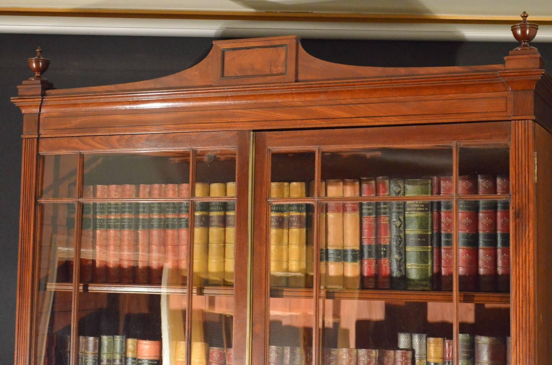 Sn3758 superb quality and very elegant, Regency, library bookcase in mahogany, having architectural pediment with finials above a pair of glazed doors enclosing three height adjustable shelves flanked by reeded corners. Base having a pair of