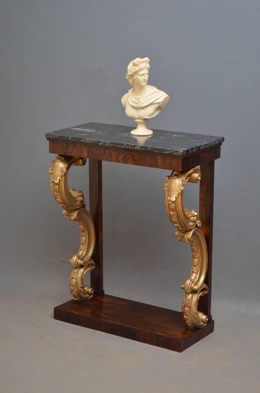 Sn3762, magnificent, regency console table of narrow proportions having stunning marble-top above rosewood frieze and excellent gilded carved legs with egg and dart decoration all terminating in platform base. This fine Regency hall table has been