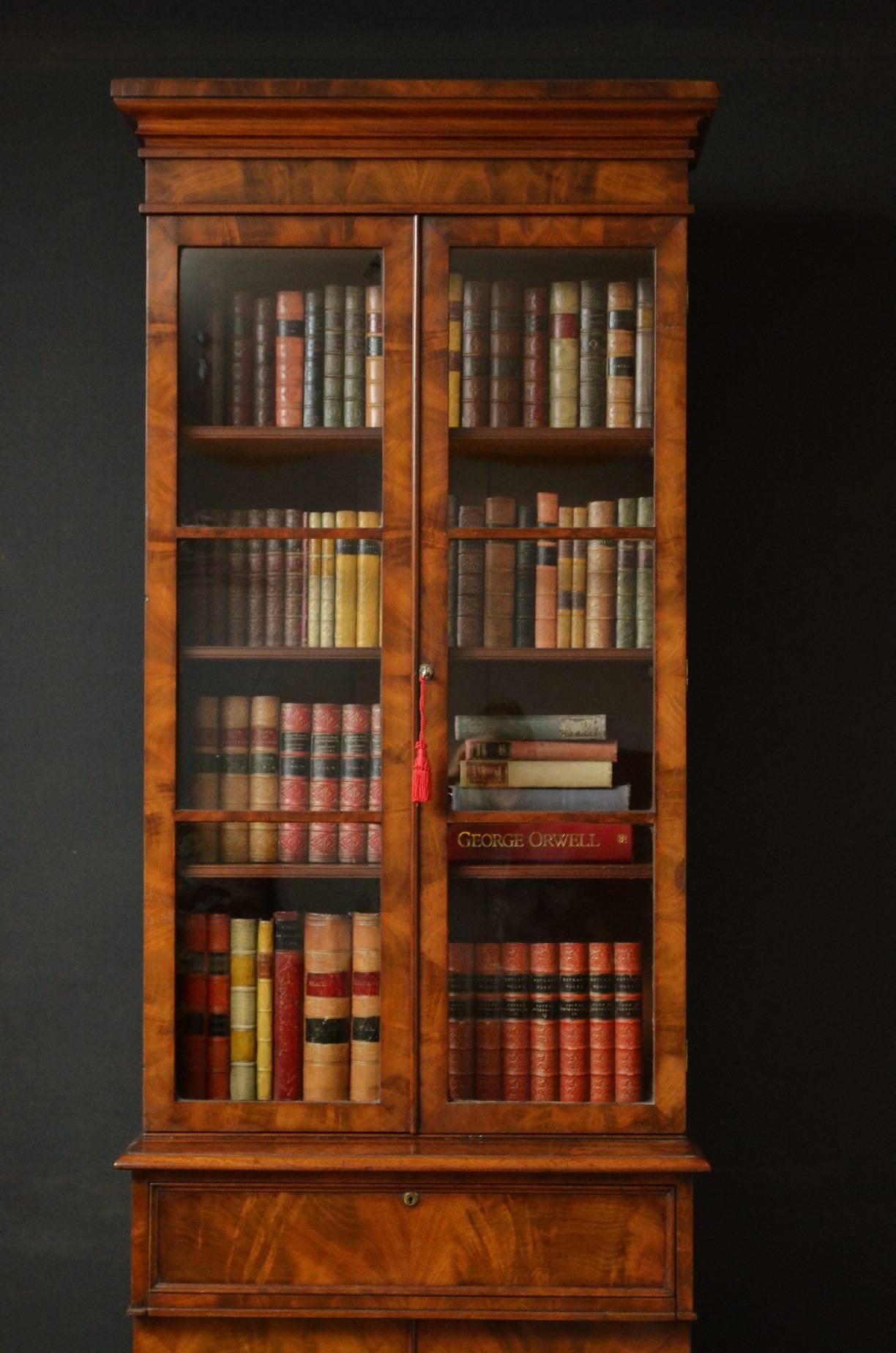 K0183, a fine quality, slim and elegant William IV mahogany bookcase, having cavetto cornice above flamed mahogany frieze and a pair of glazed doors enclosing three height adjustable shelves, the base having deep oak lined drawer above a pair