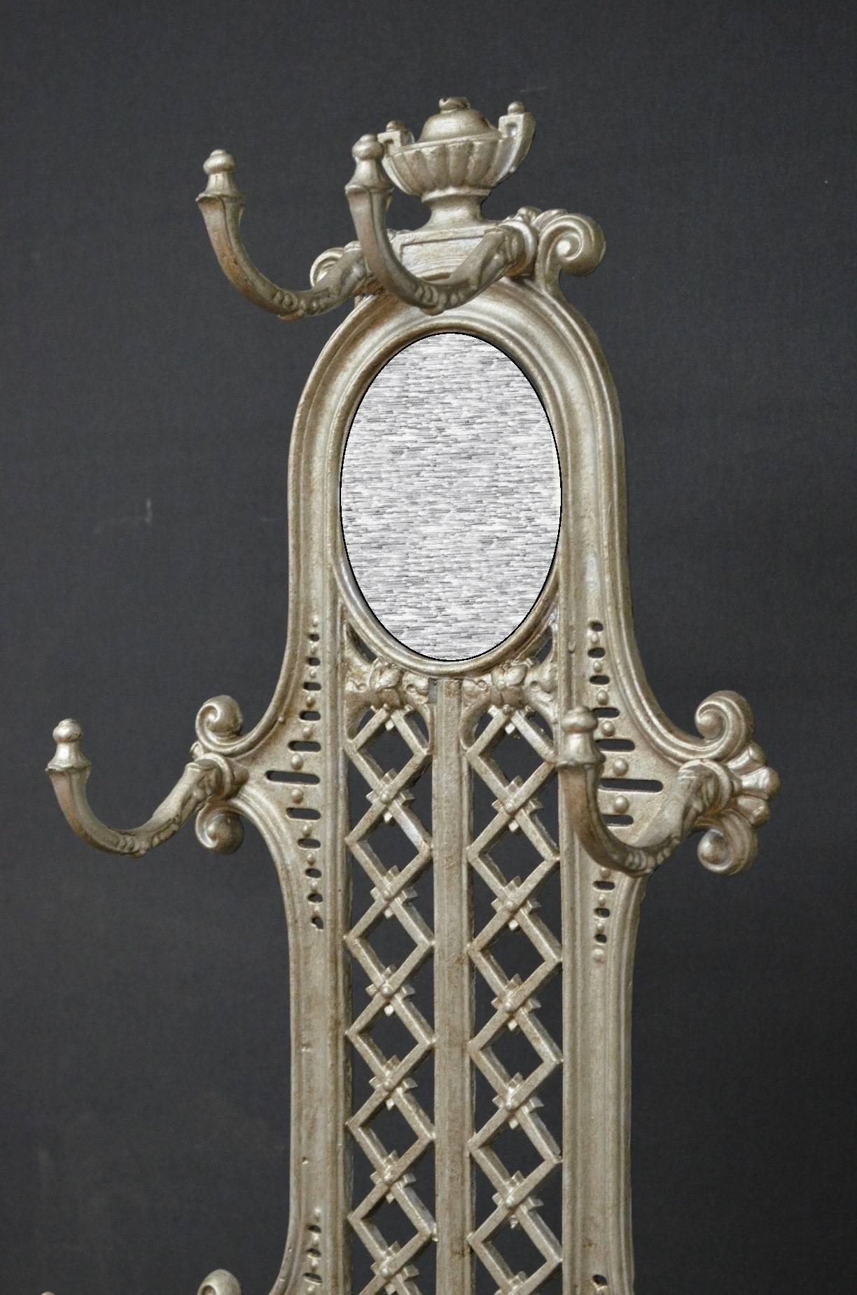K098 excellent Victorian cast iron hall stand or coat stand, having shaped top with oval mirror flanked by scrolling coat hooks, the lower section with cast iron shaped umbrella and stick holder and original drip tray, all raised on shaped platform.