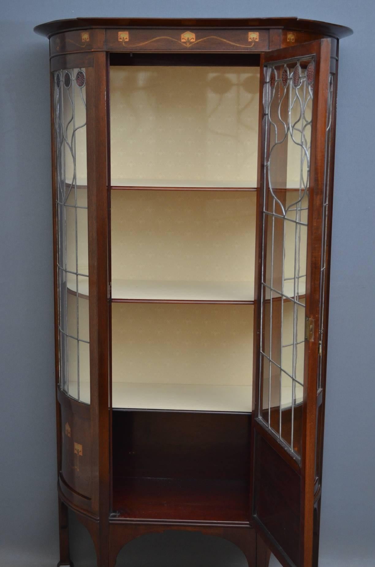 Sn4125 Art Nouveau mahogany display cabinet / vitrine, having outswept cornice with finely inlaid frieze, leaded glass door enclosing relined interior with three shelves and cupboard, all flanked by bowed glazed sides with panelled and inlaid