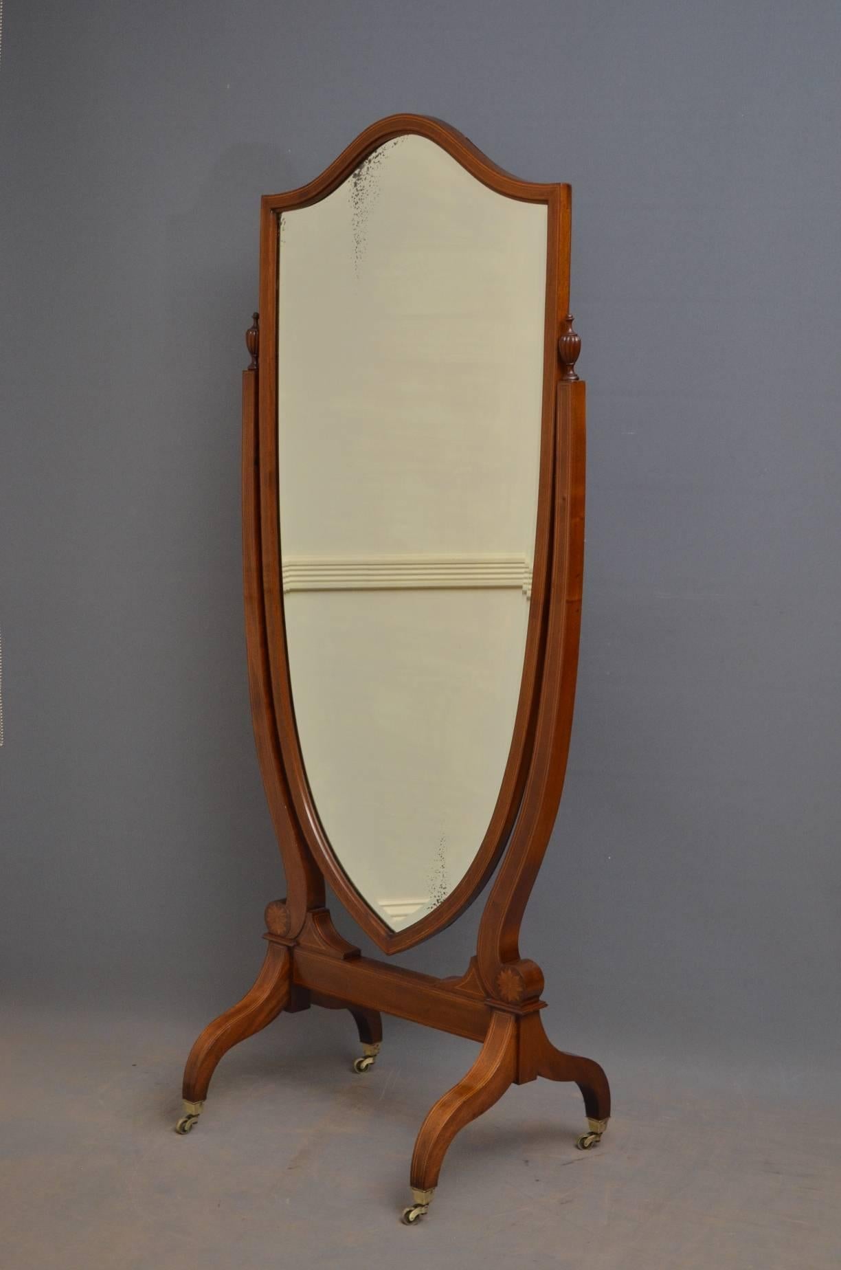 Sn4126 Edwardian mahogany and inlaid, shield shaped cheval mirror, having original bevelled edge mirror in inlaid frame and finely inlaid supports with original fluted finials to top and fan inlays to base, standing on downswpet legs terminating in