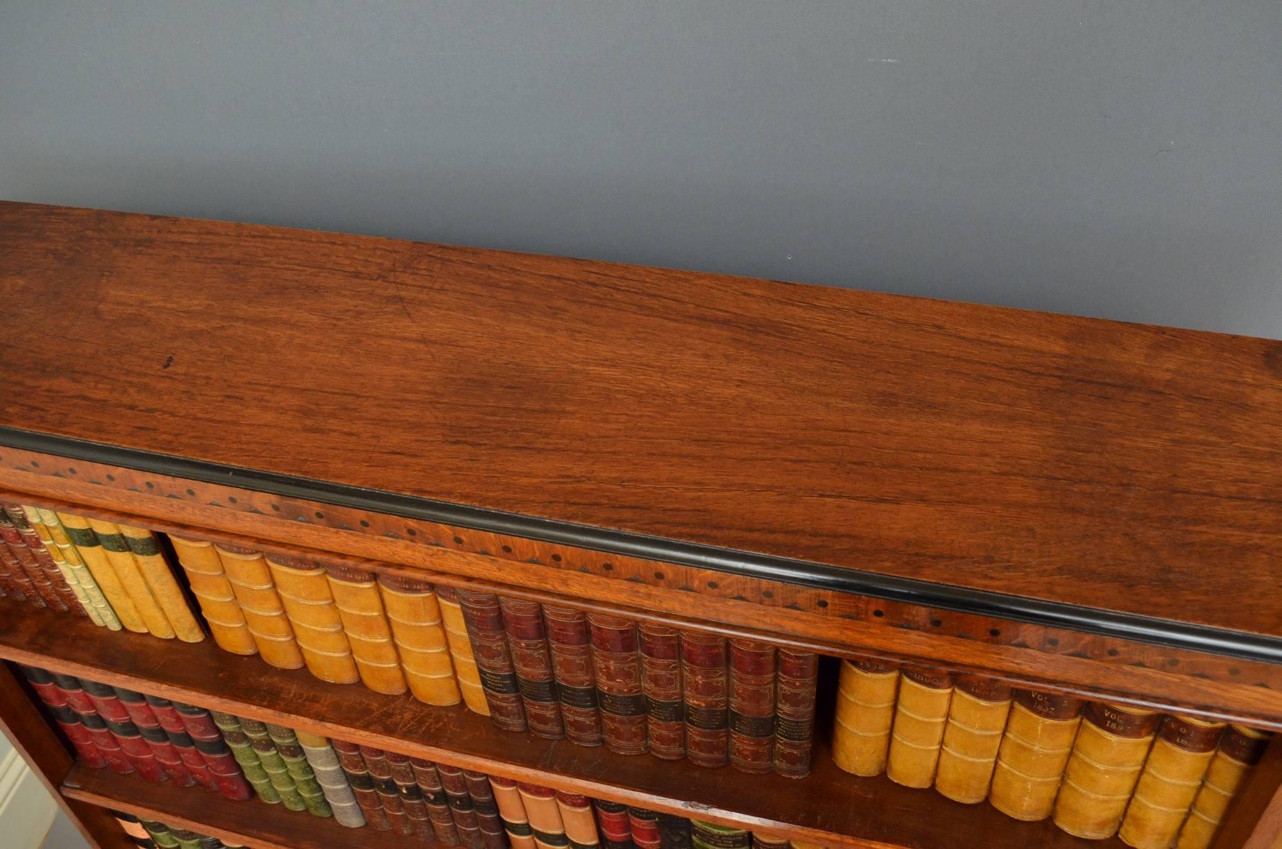 J00 late Victorian, Aesthetic Movement oak open bookcase, having moulded top with ebonized edge above three height adjustable shelves flanked by canted string inlaid pilasters, all standing on plinth base. This bookcase retains its original finish,