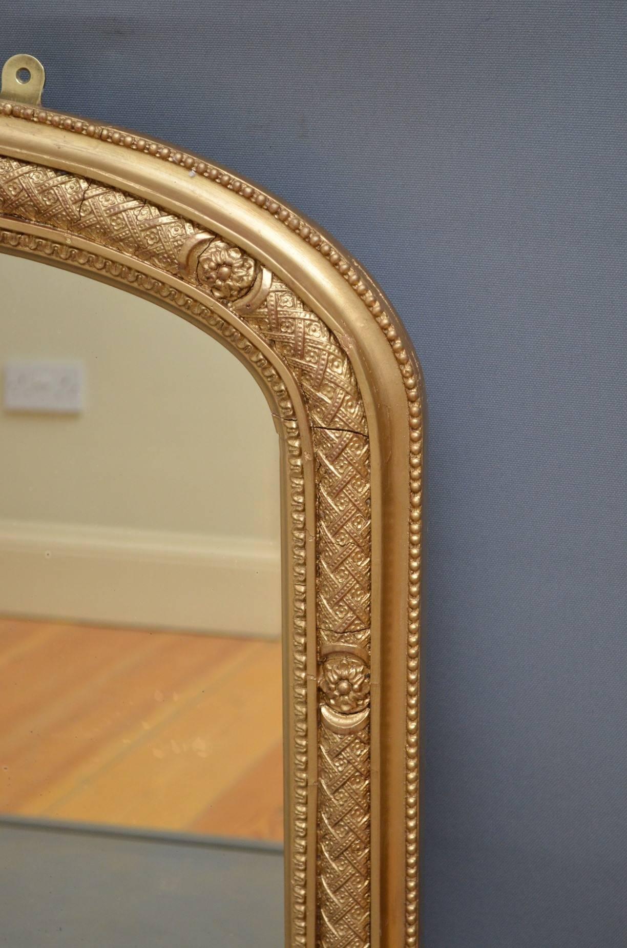 K0242 Victorian gilt overmantel of arched form with original mirror plate in finely decorated and beaded frame with foliate carvings to sides and original porcelain feet. This stunning wall mirror has been refinished and is in wonderful condition