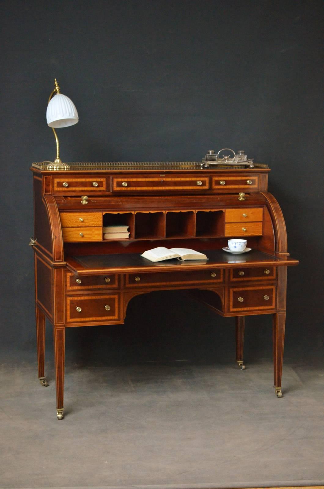 Sn4216 An exhibition quality cylinder desk in mahogany, having brass gallery to top and three satinwood cross banded drawers fitted with original brass handles above cylinder front which open to reveal small drawers, pigeon holes and black tooled