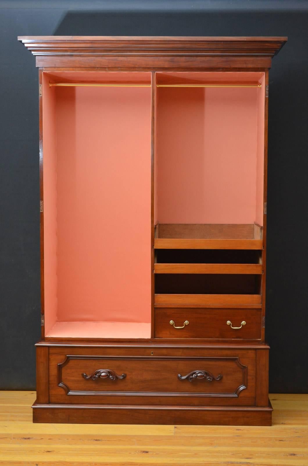 Sn4210 A Victorian two-door wardrobe in mahogany with cavetto cornice, pair of arched and panelled figured mahogany doors enclosing hanging sections and sliders above deep base drawer fitted with finely carved handles, all standing on plinth base.