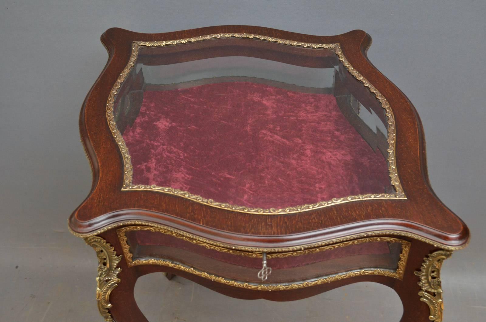 Sn4248 Edwardian mahogany display table of shaped outline, having hinged lid with bevelled edge glass and original working lock enclosing crushed velvet interior, all standing on cabriole legs terminating in sabots. This antique display table is