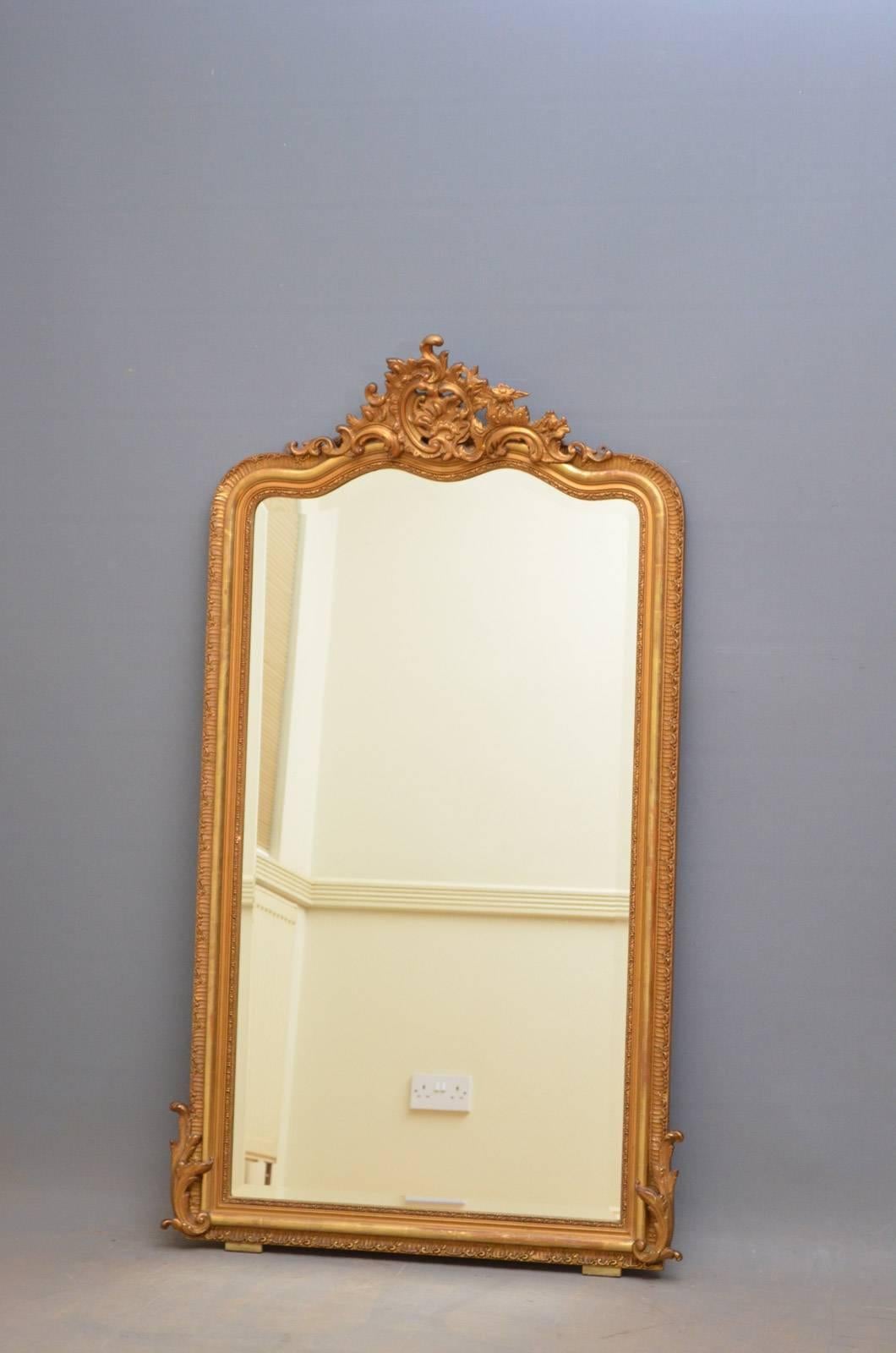 J00 Vergoldeter Spiegel aus der Jahrhundertwende, mit fein geschnitzter Kartusche in der Mitte und ursprünglicher Spiegelplatte mit abgeschrägter Kante und einigen Stockflecken im geschnitzten Rahmen. Dieser antike Spiegel behält seine ursprüngliche