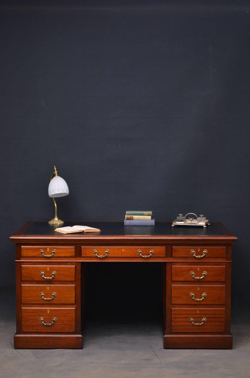 Sn4303, a large mahogany desk with panelled sides and black tooled leather top above three fielded drawers and three graduated drawers to each pedestal, all fitted with original brass handles and flanked by reeded pilasters, standing on plinth base