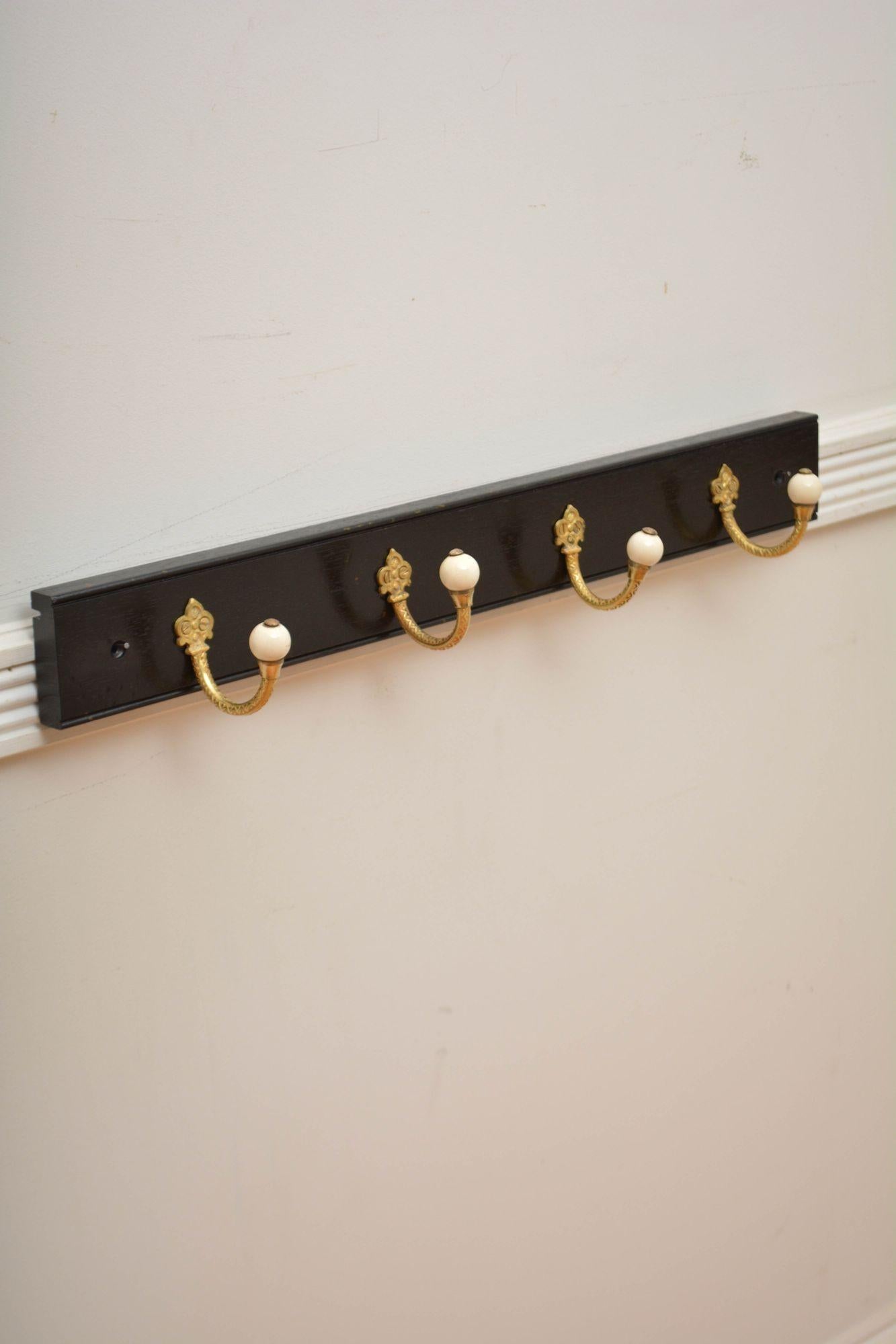 K0311 Brass and ceramic set of four very decorative Victorian coat hooks now on solid mahogany ebonised backing.  Cleaned, polished and ready to place at home. 

H3 1/4