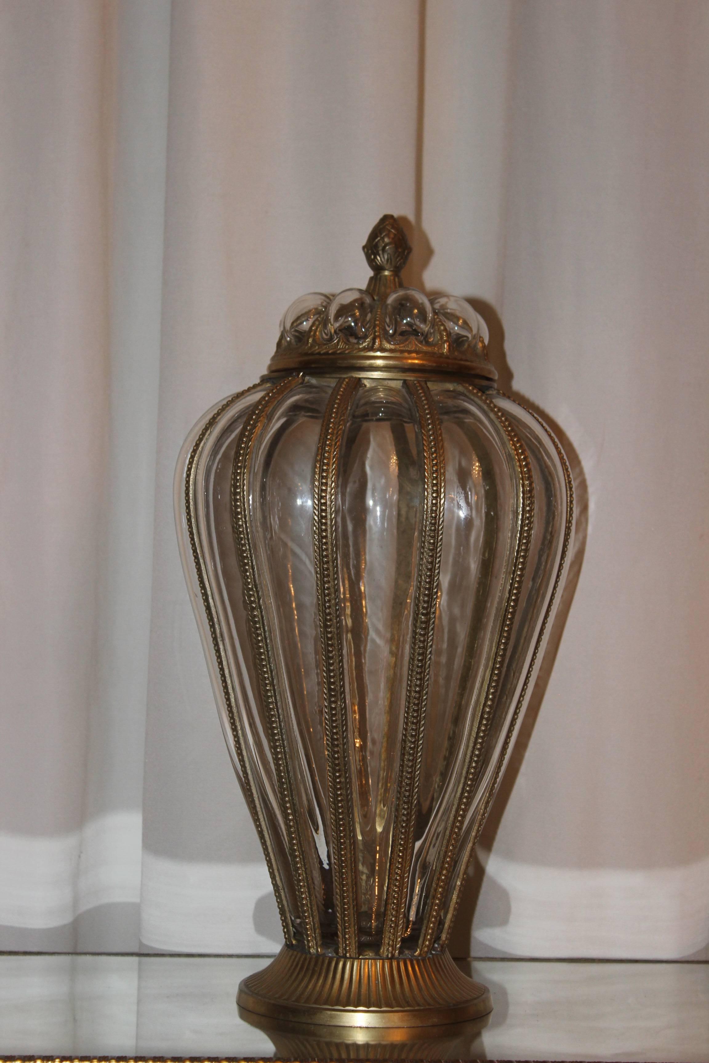 This is an Italian made handblown glass and brass vase with the clear glass being blown into a brass molded skeleton body. 

This type of work is more often associated with wrought iron framed bodies, usually as ceiling shades, with the glass being