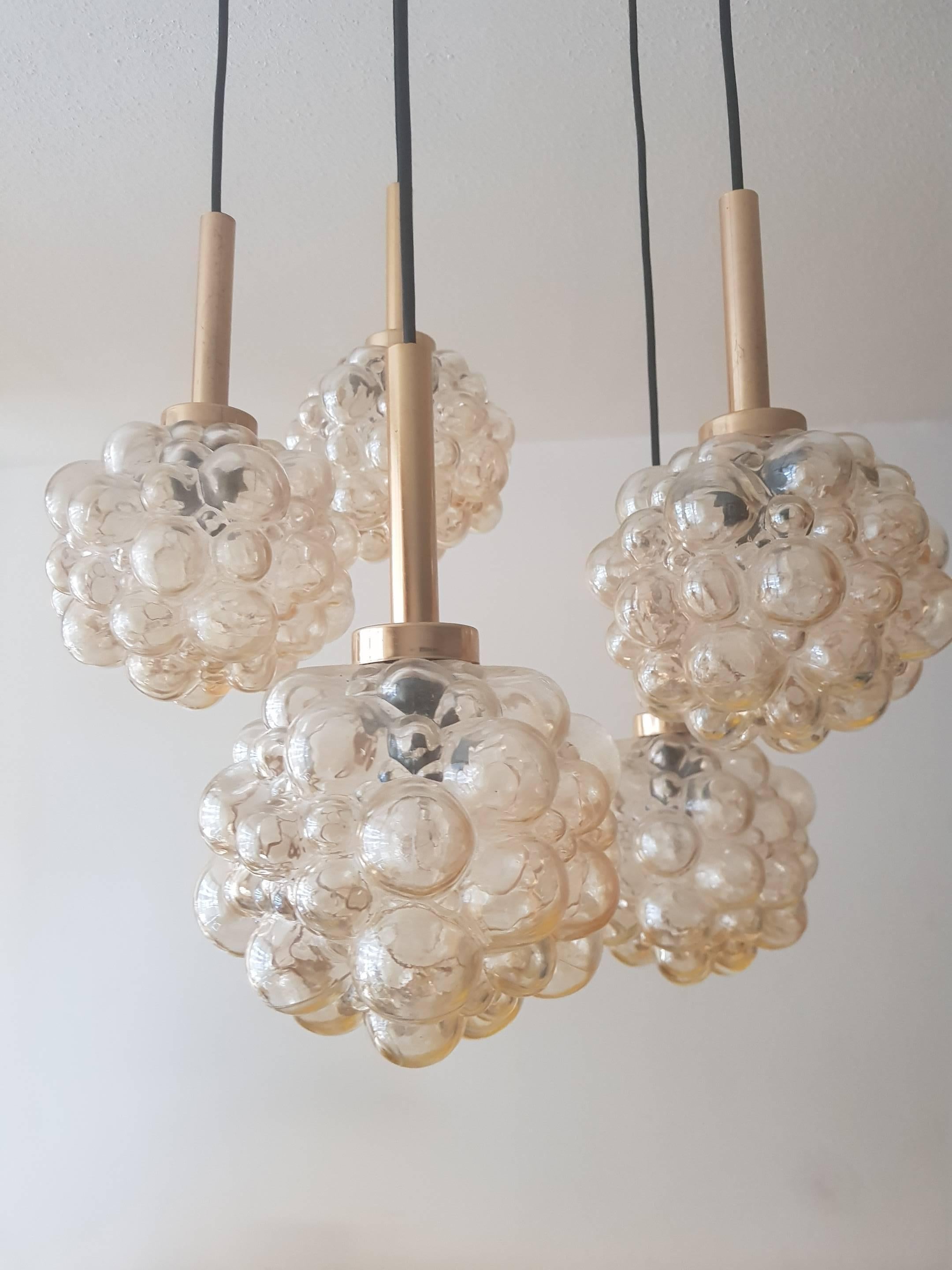Bubble chandelier by Helena Tynell a designer from Finland. This design is from the 1960s. The chandelier has 5 lights with glass shade of iridescent, amber-colored bubble glass, hangs on an elegant brass linkage
Length of wire can be