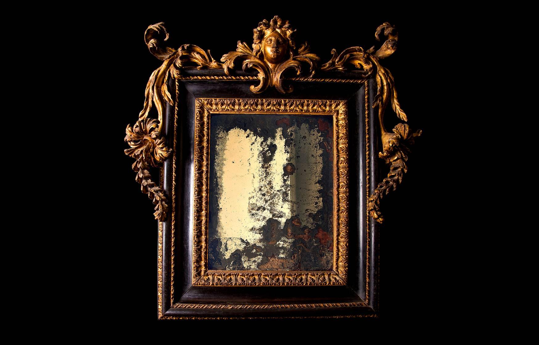 An astonishing Baroque mirror, provenance - Palazzo Sacchetti, Rome. Of rectangular form, the cresting with the female mask flanked by boldly scrolled acanthus, the rectangular plate within a foliate concave and twisted-ribbon border.