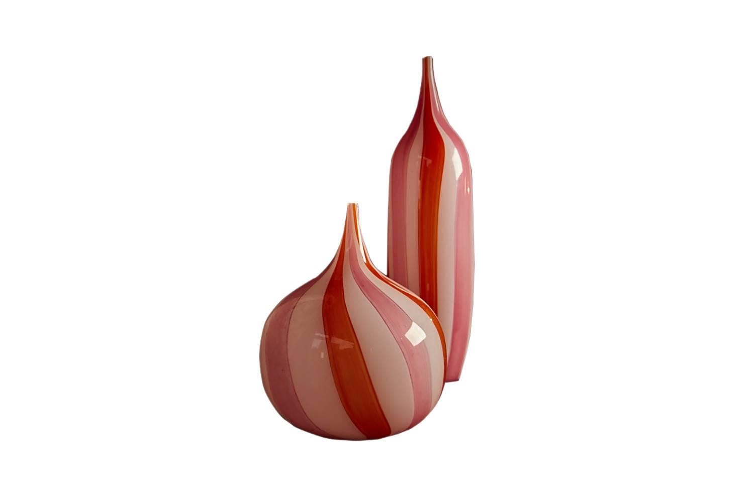 Rare to find a pair of Murano vases of this design and complimentary size. One of tall cylindrical form, the other of a characteristic round 'onion' shape. With twisted barley glaze in Vermillion, candy pink and white with a wonderful translucency.