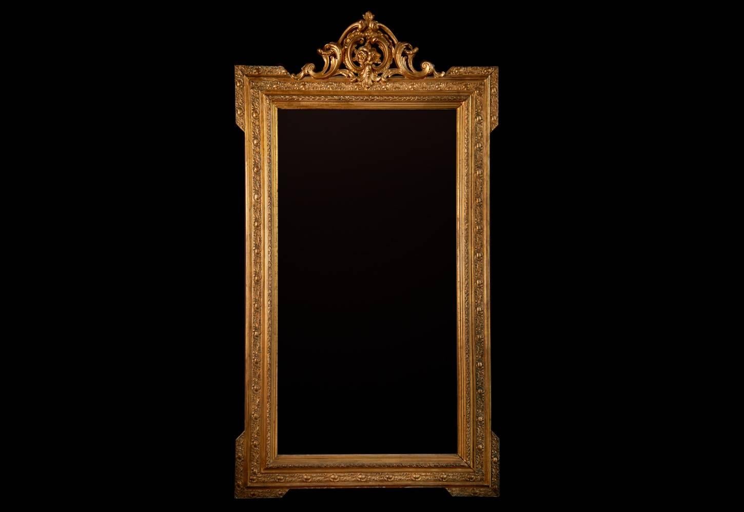 Wonderfully decorative, ornate and grand scale Neo-classical Napoleon III gilt wall mirror. Crested with ribbon and foliate gesso work, crest surmounting extensively carved relief moulded frame enclosing original bevel plate mirror. 