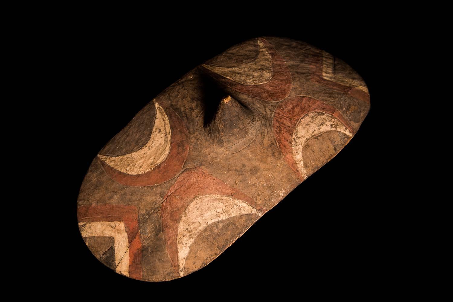 An elliptical shield of the Tutsi tribe of Burundi. More high than wide and oval in design with looped handle, this shield is made of light wood and is folded inwards. Also used for dancing and rituals, the motifs are variable - in this case