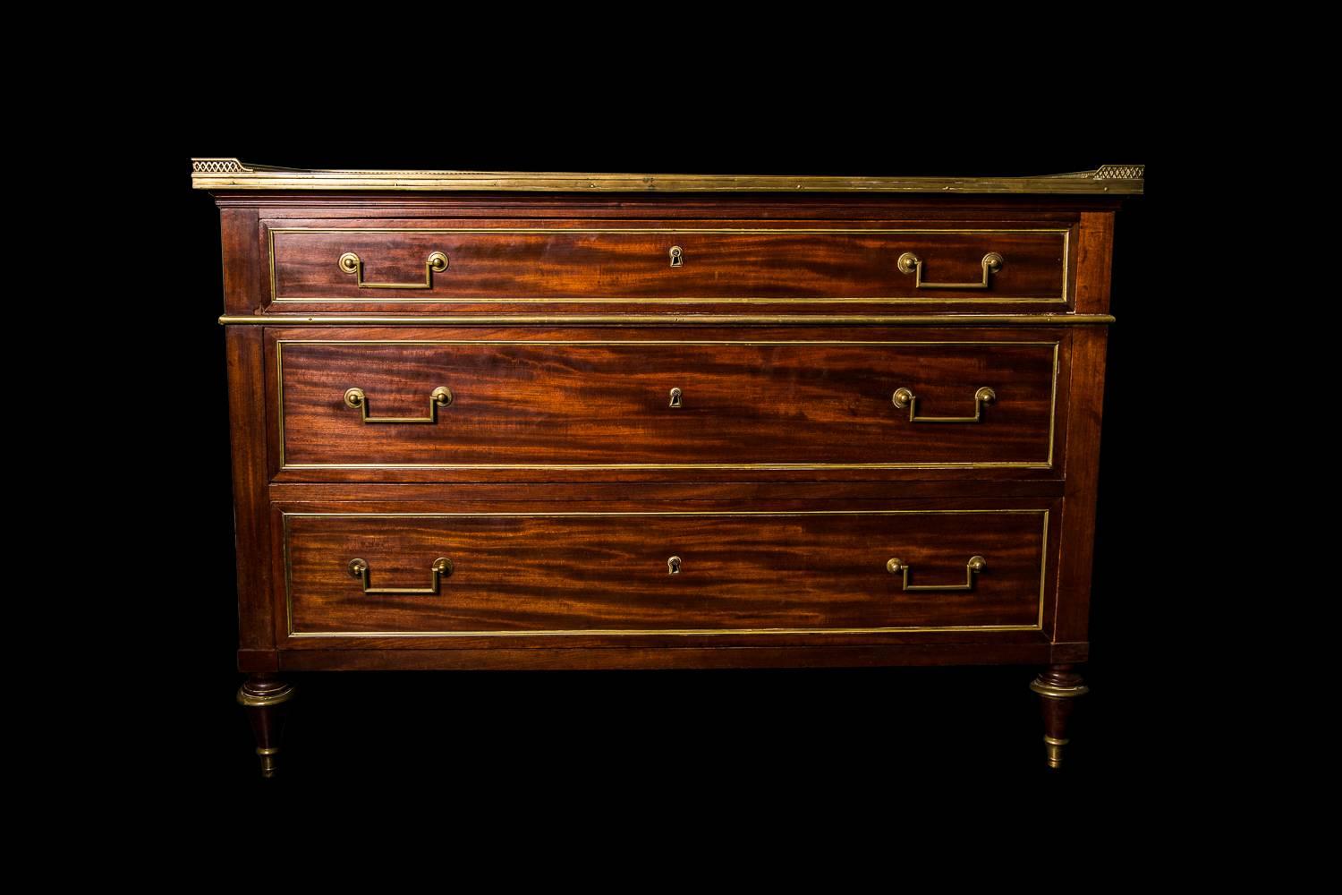 With feature pierced gallery above three long graduated drawers with brass mouldings, raised on toupe turned legs with brass collers and sabots.