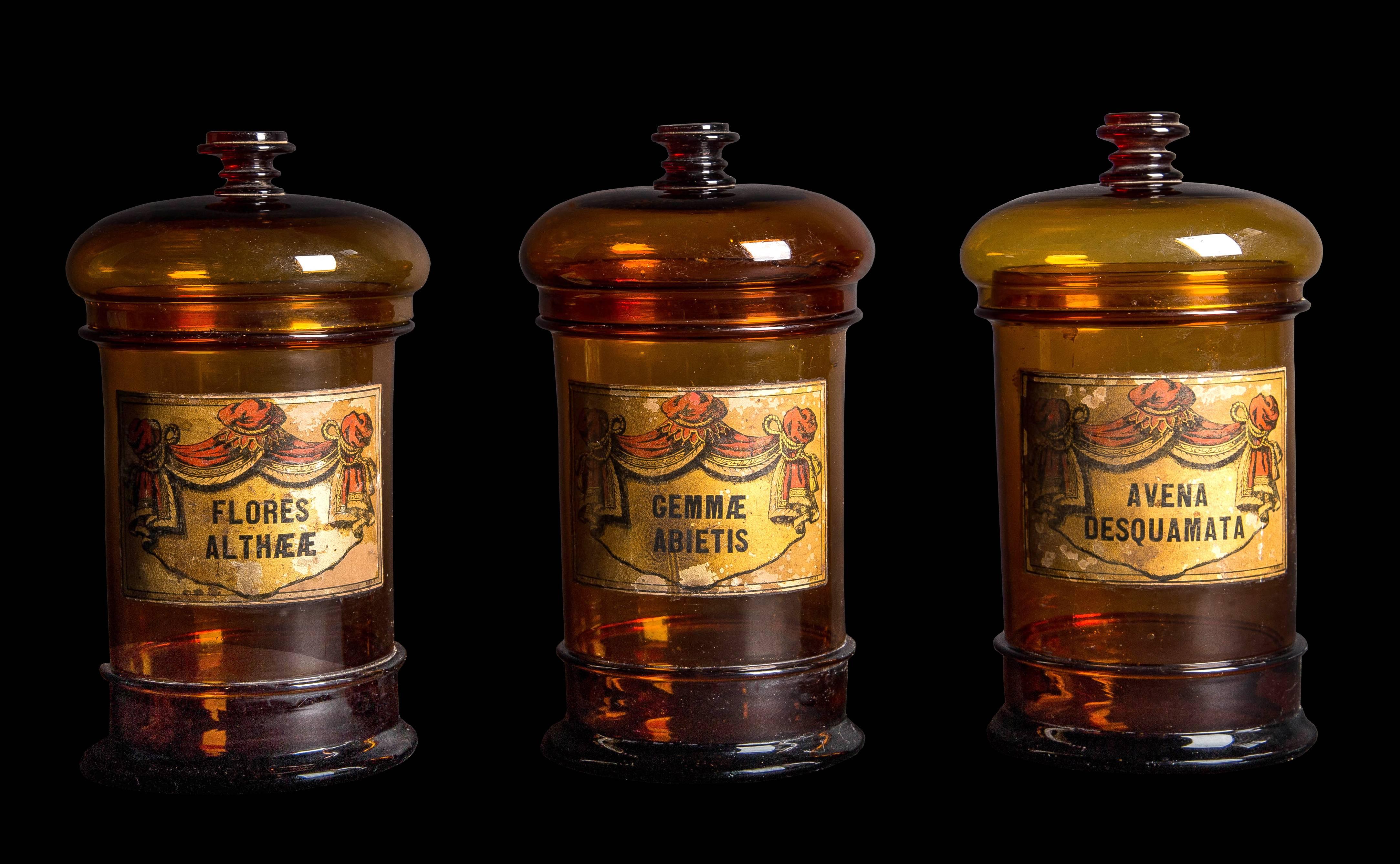So rare to find now, of dramatic scale and architectural form - a set of three handblown amber glass apothecary jars with beautiful balloon shape lids and fob handles, mid-19th century. All in excellent condition. The labels are highly decorative