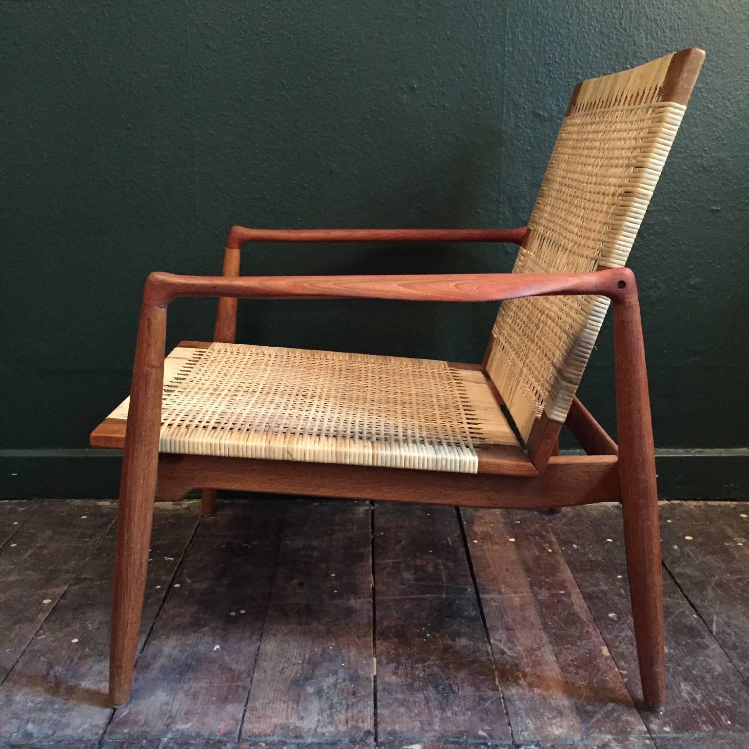 This beautiful piece of furniture was designed by Finn Juhl in 1954 and produced until 1959. It was produced by Danish cabinetmaker Soren Willadsen. The frame and legs are solid oak. The armrests are teak. The chair is upholstered with woven cane.