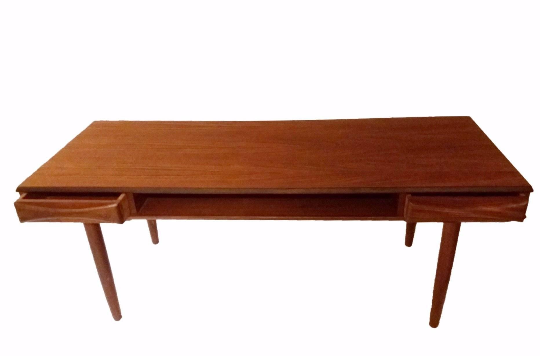 This Danish 1950s Arne Vodder style teak coffee table comes with a central book shelf and 