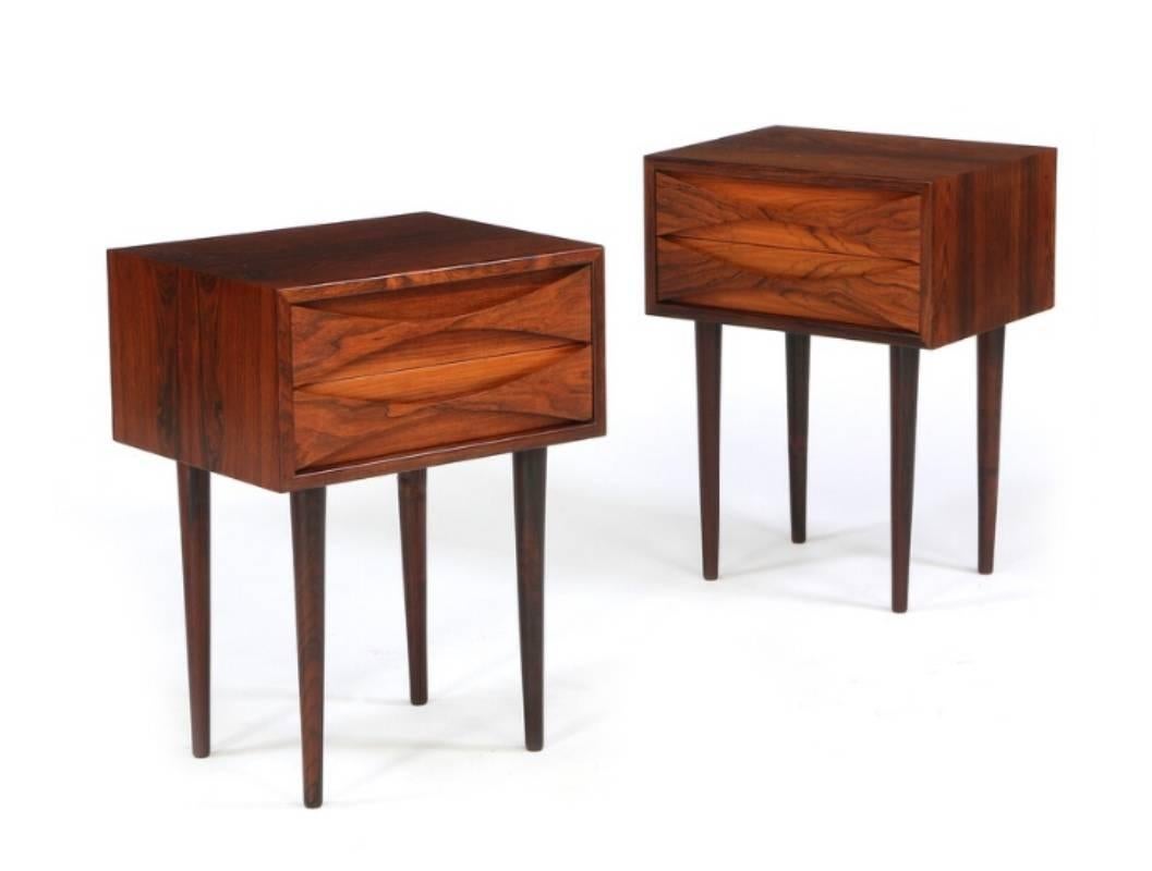 A pair of tall rosewood nightstands with solid tapered legs and two drawers designed by Arne Vodder. They have a slight color difference, but they are in excellent condition. 

Arne Vodder is one of the most influential Scandinavian architects in