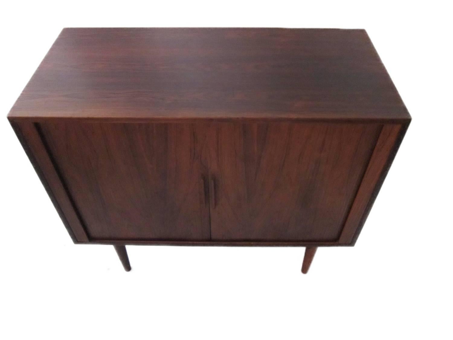 Small Danish sideboard in rosewood with sliding doors and shelves inside designed by Kai Kristiansen. It has tapered legs in solid rosewood as well and a stunning shape.

It is refurnished and comes in excellent vintage condition.
 
