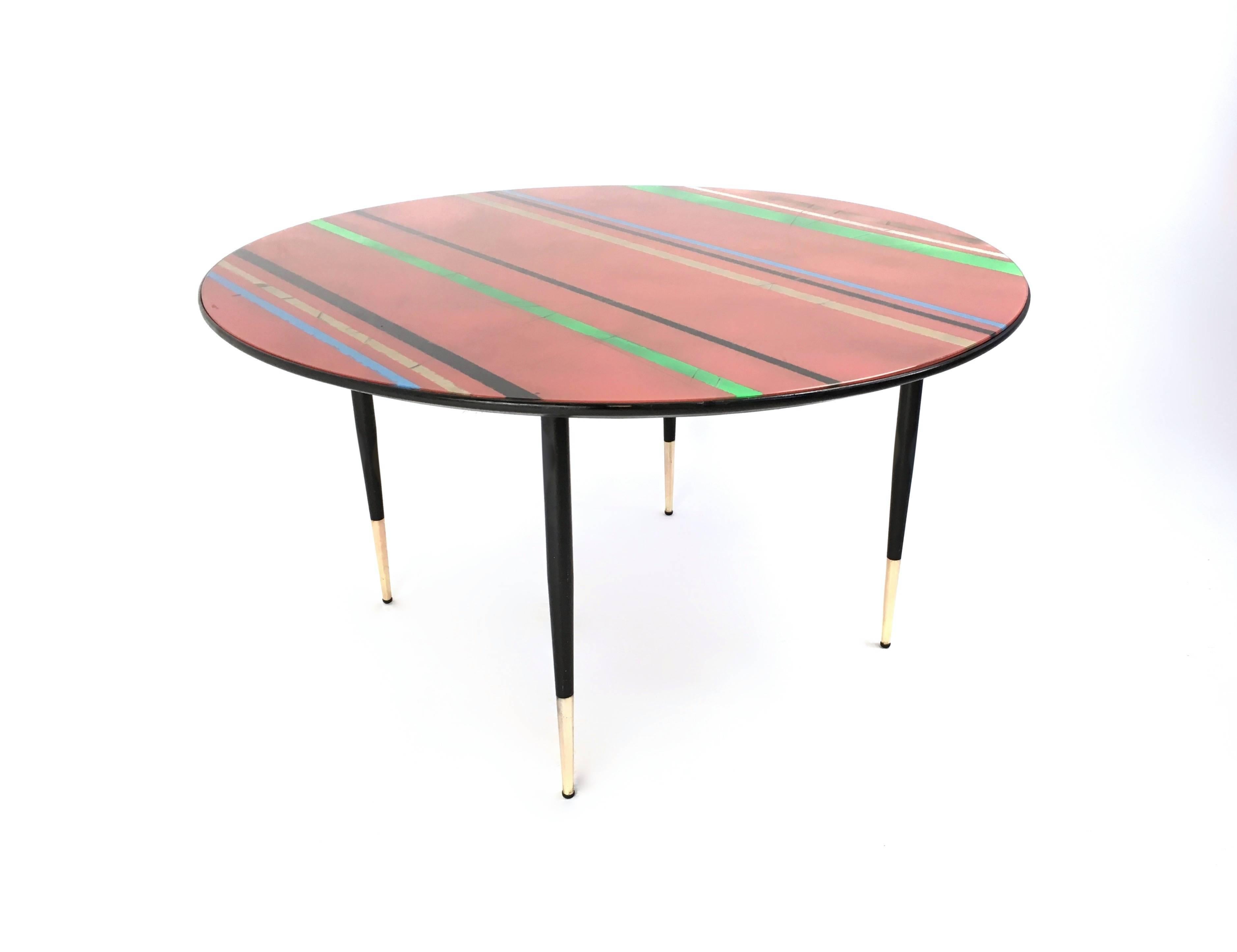 Made in Italy, 1950s. 
This coffee table features a wooden frame with iron legs and brass feet caps, and a back-painted glass top.
It is a vintage item, therefore it might show slight traces of use, but it can be considered as in very good original