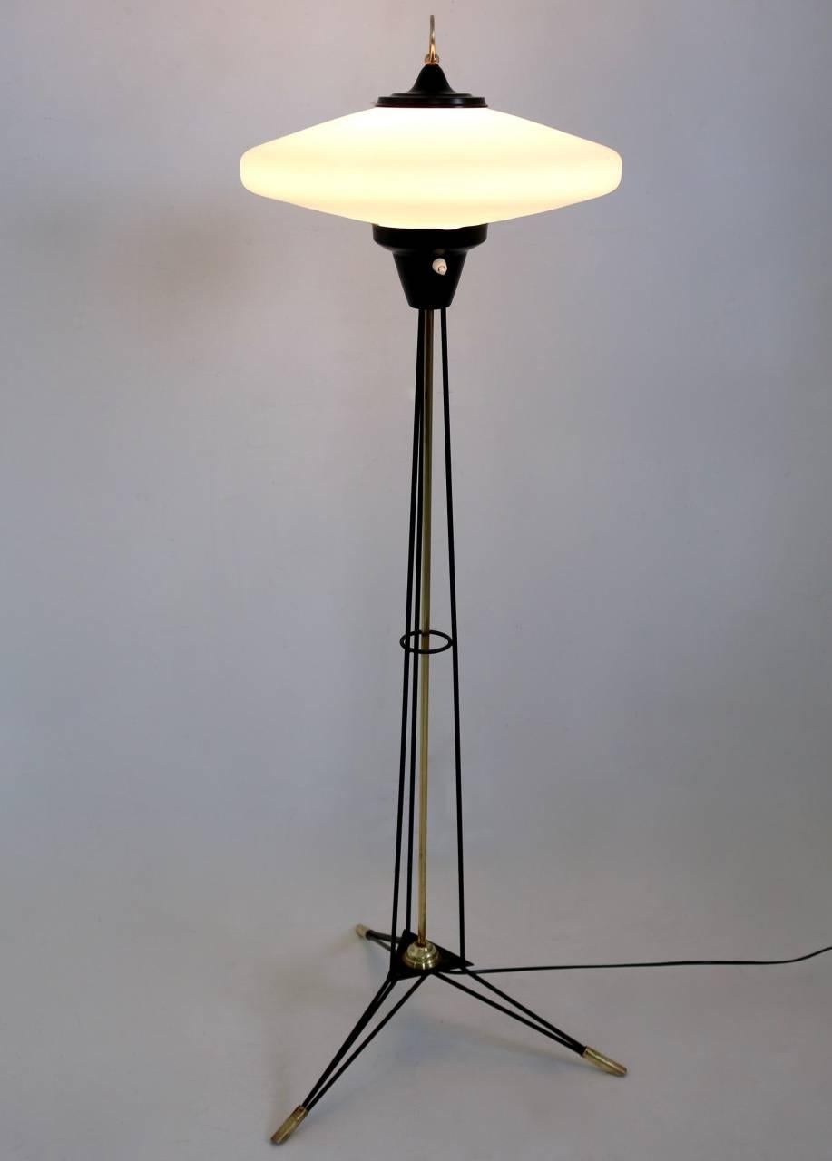 This is a beautiful Stilnovo floor lamp on tripod legs made with brass and black lacquered metal. 
It features a brass ring on a black lacquered base mounted on top.
The wiring is new, as it has been perfectly restored.
Made in Italy. 
In excellent