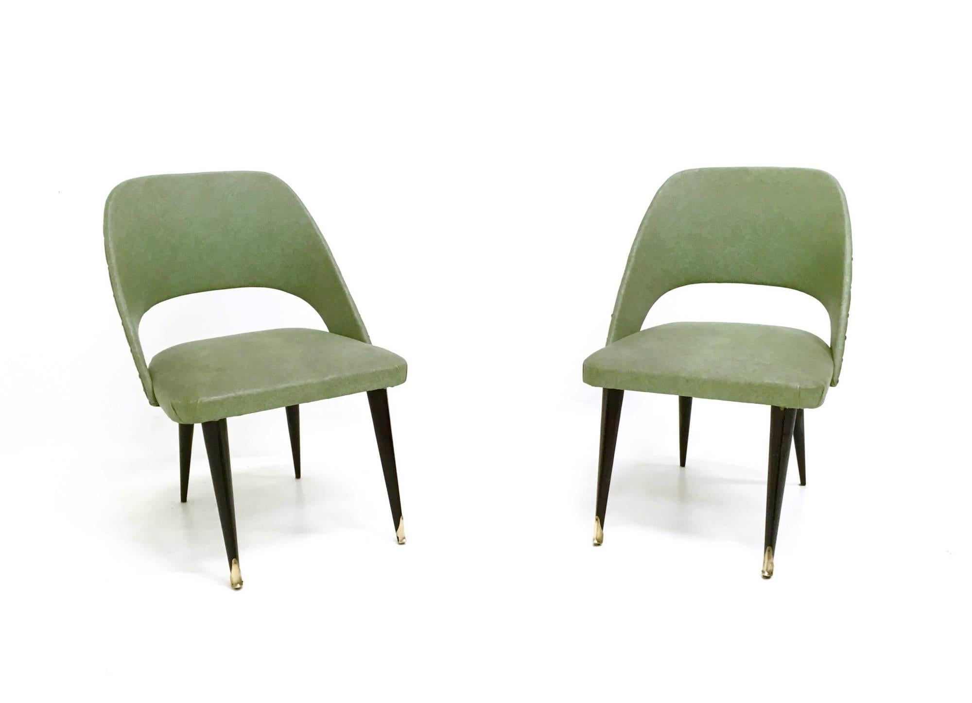 They feature a wooden structure upholstered in vintage skai and ebonized wood legs with brass feet caps. 
In good original condition.