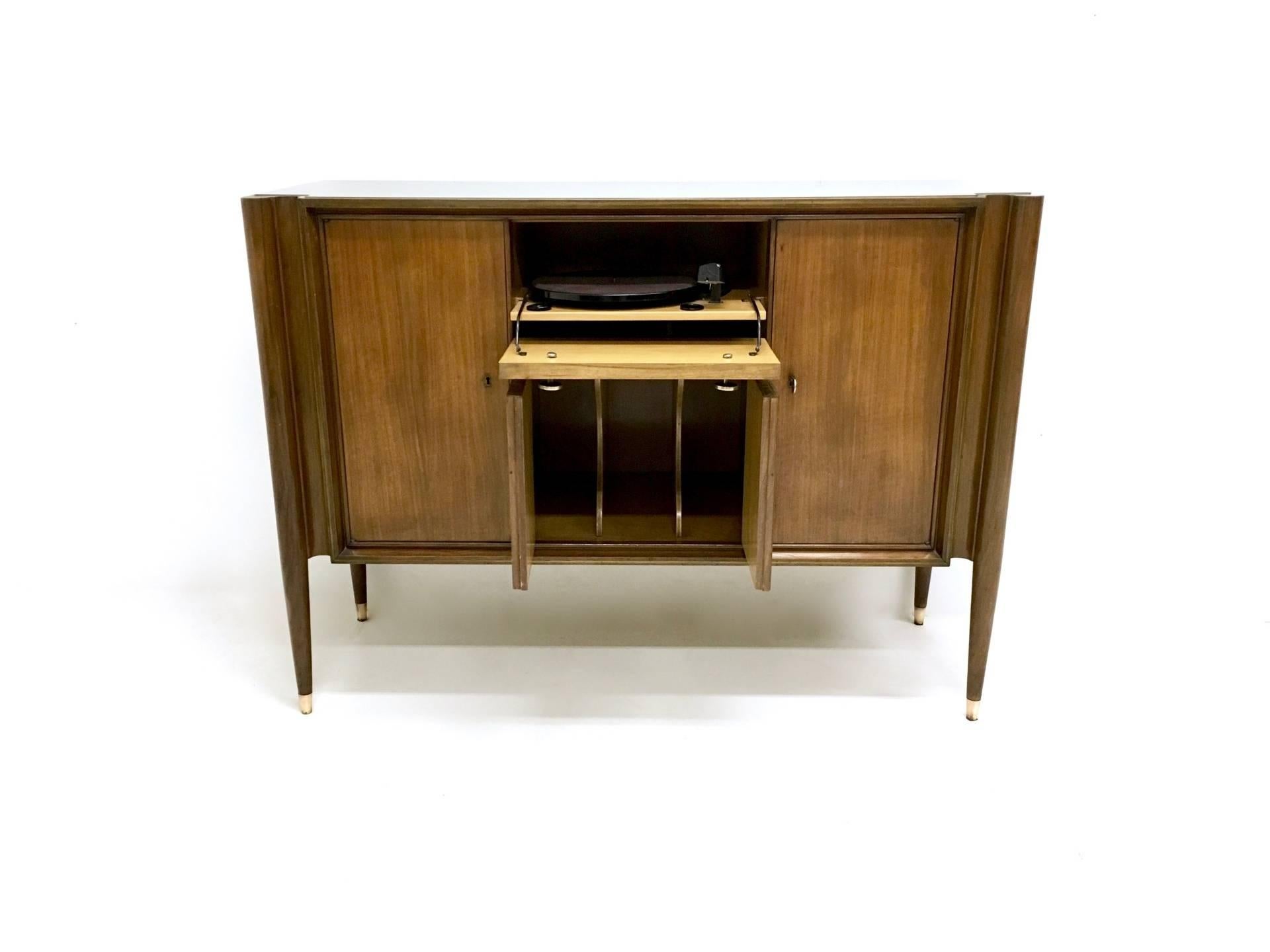 It is a high-quality cabinet, which is made in walnut and features brass and nickel-plated metal parts. 
On the inside it has mirrored walls. 
It has a back-painted glass top.
In good original condition. 


