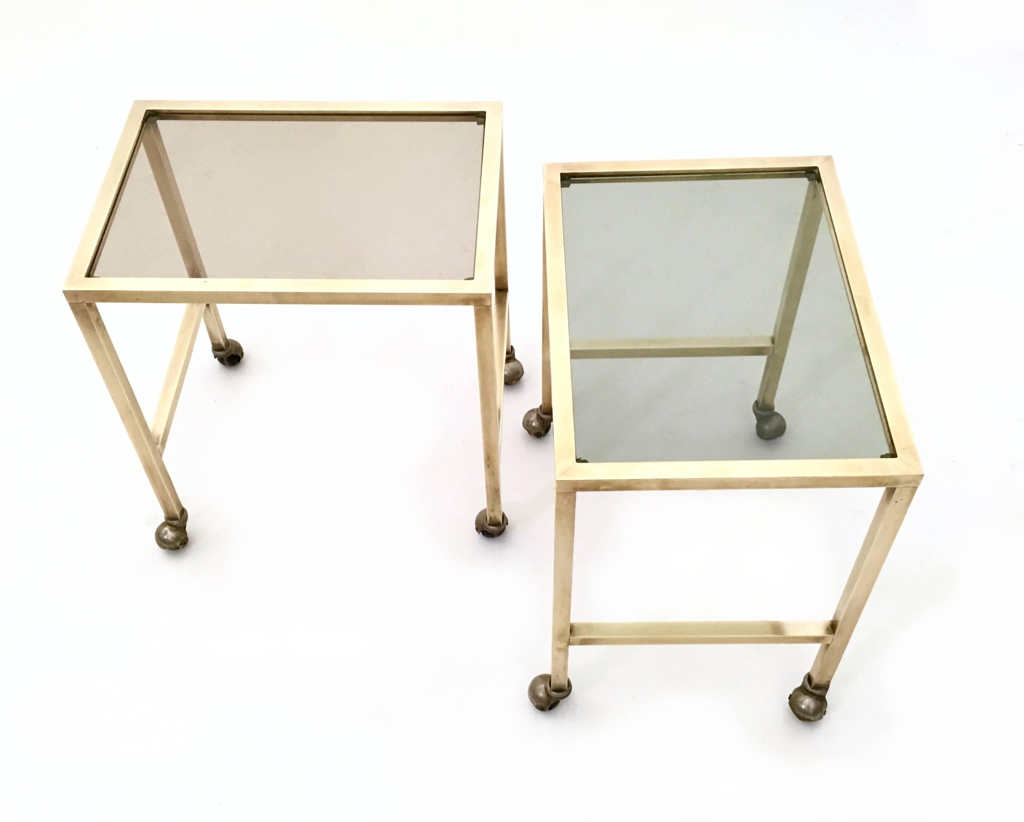 They feature a brass structure and a smoked glass top.
What is interesting about these two nightstands is that they are on casters.
In very good original condition.